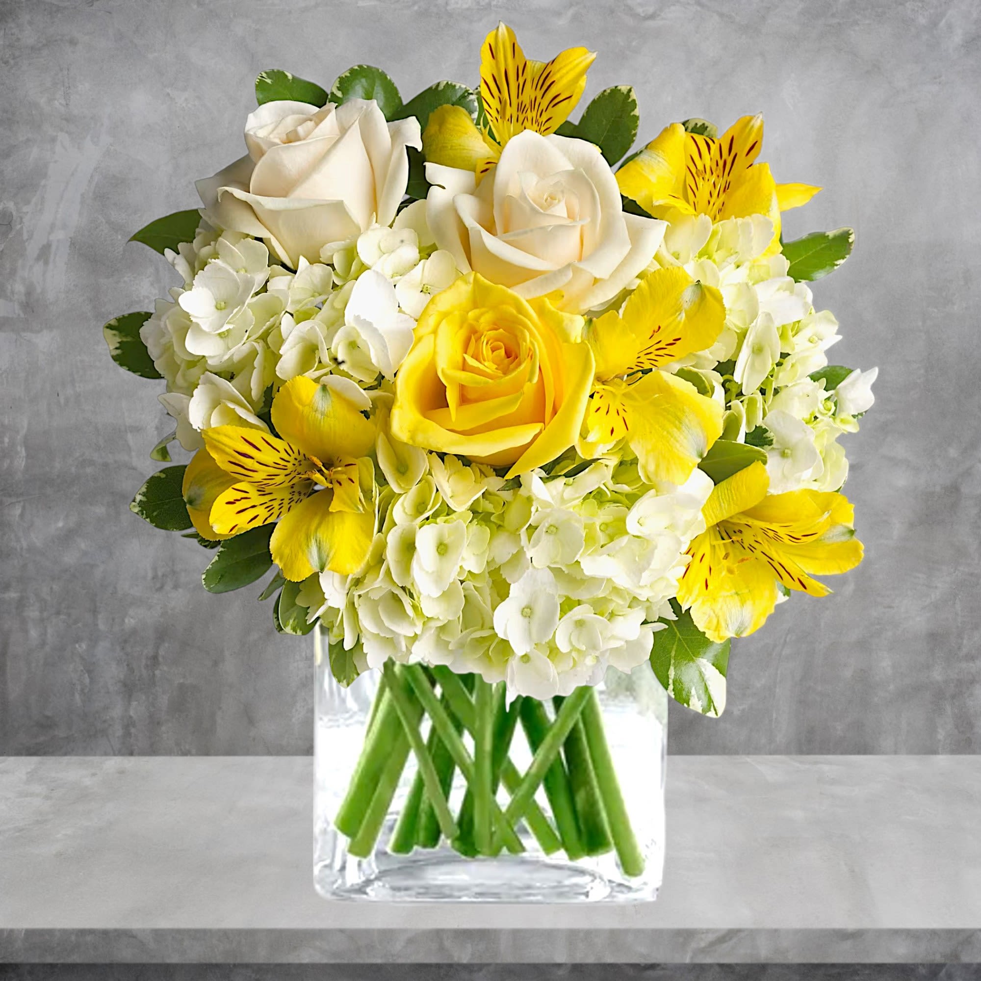 Yellow and white roses with alstroemeria in a clear glass vase