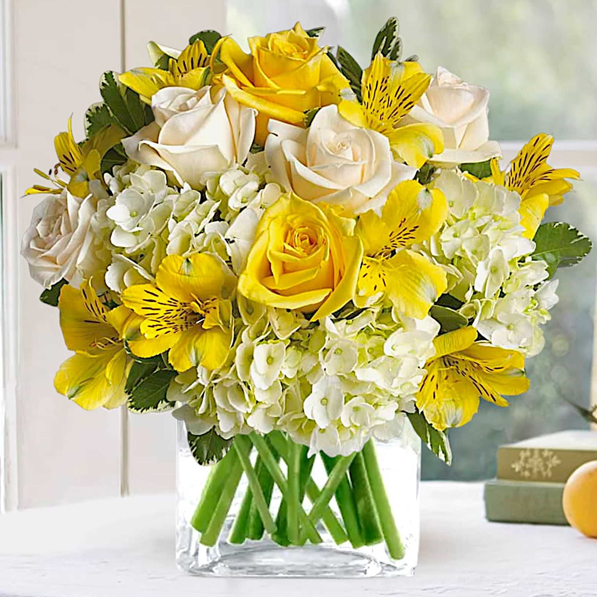 Yellow and white roses with white hydrangeas in a clear glass vase, photo 2 of 3