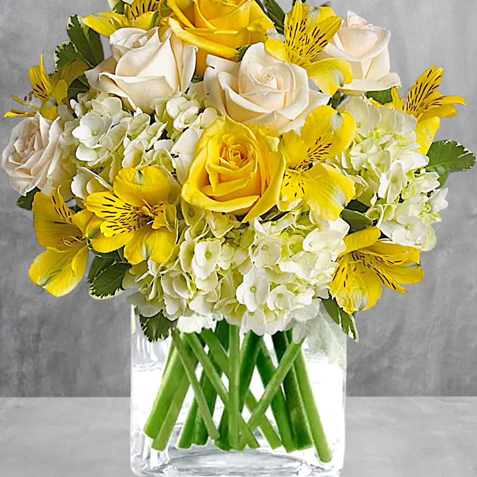 Yellow and white roses with white hydrangeas in a clear glass vase, photo 3 of 3