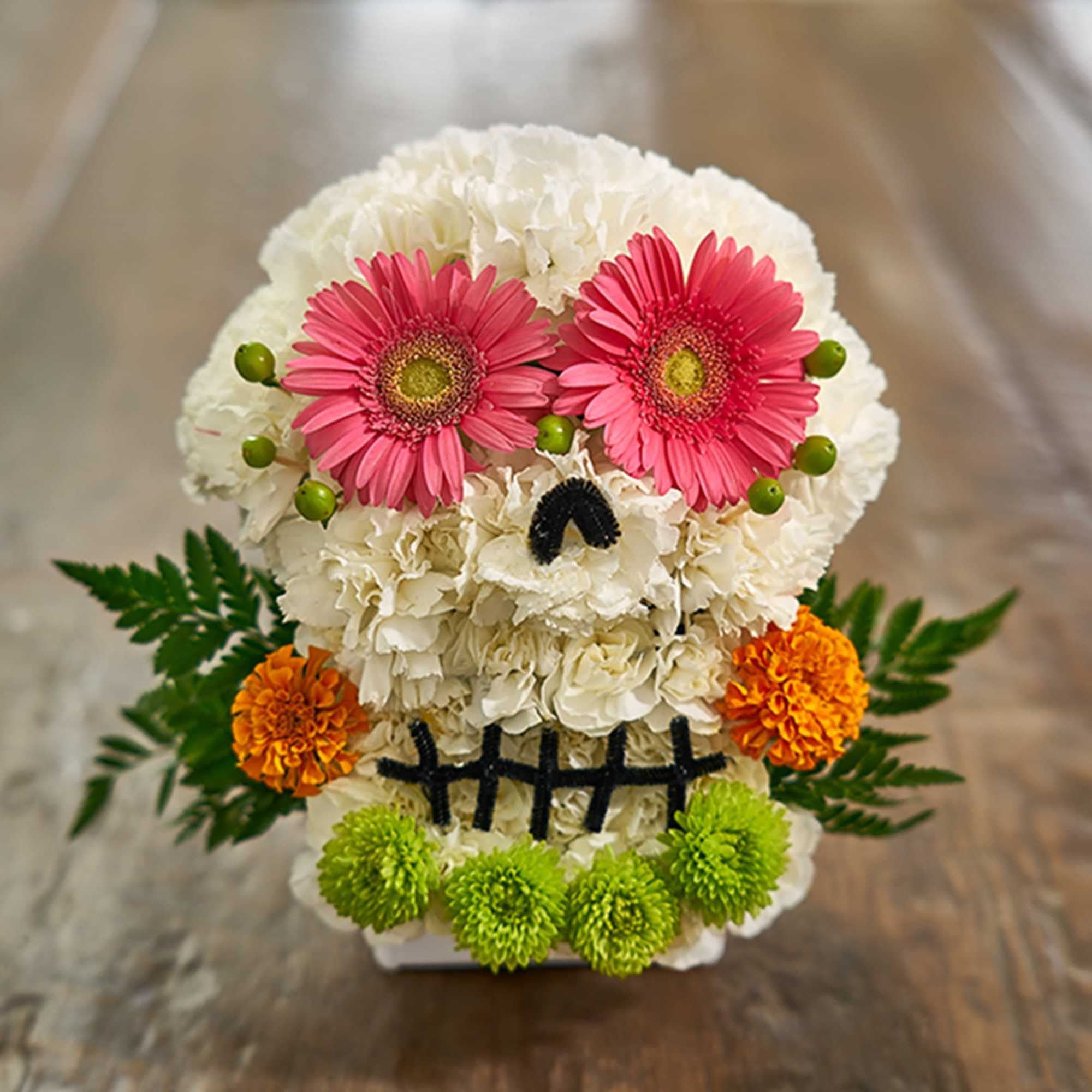 Skull-shaped floral arrangement with pink daisies and white blooms