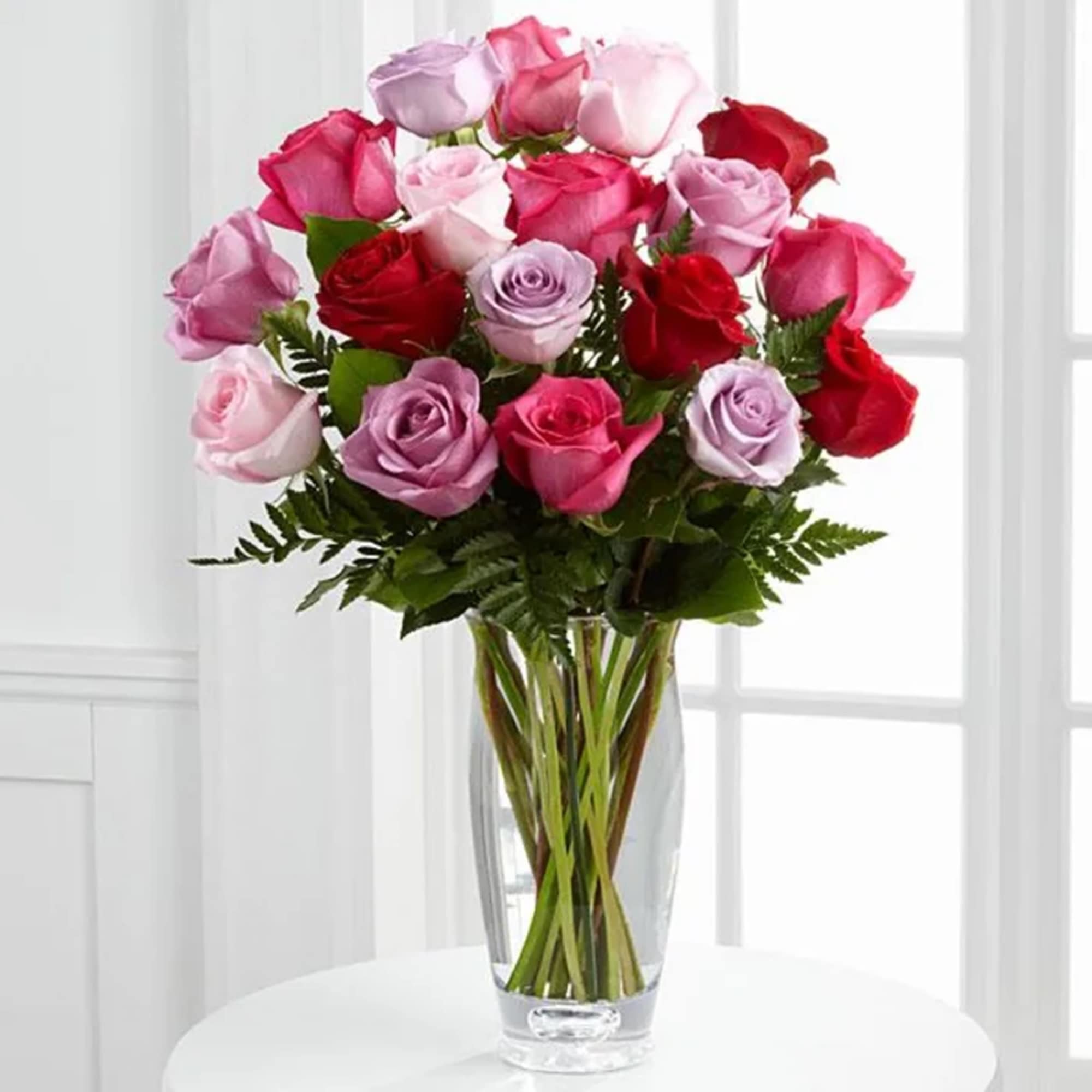 Bouquet of pink, red, and lavender roses in a clear glass vase