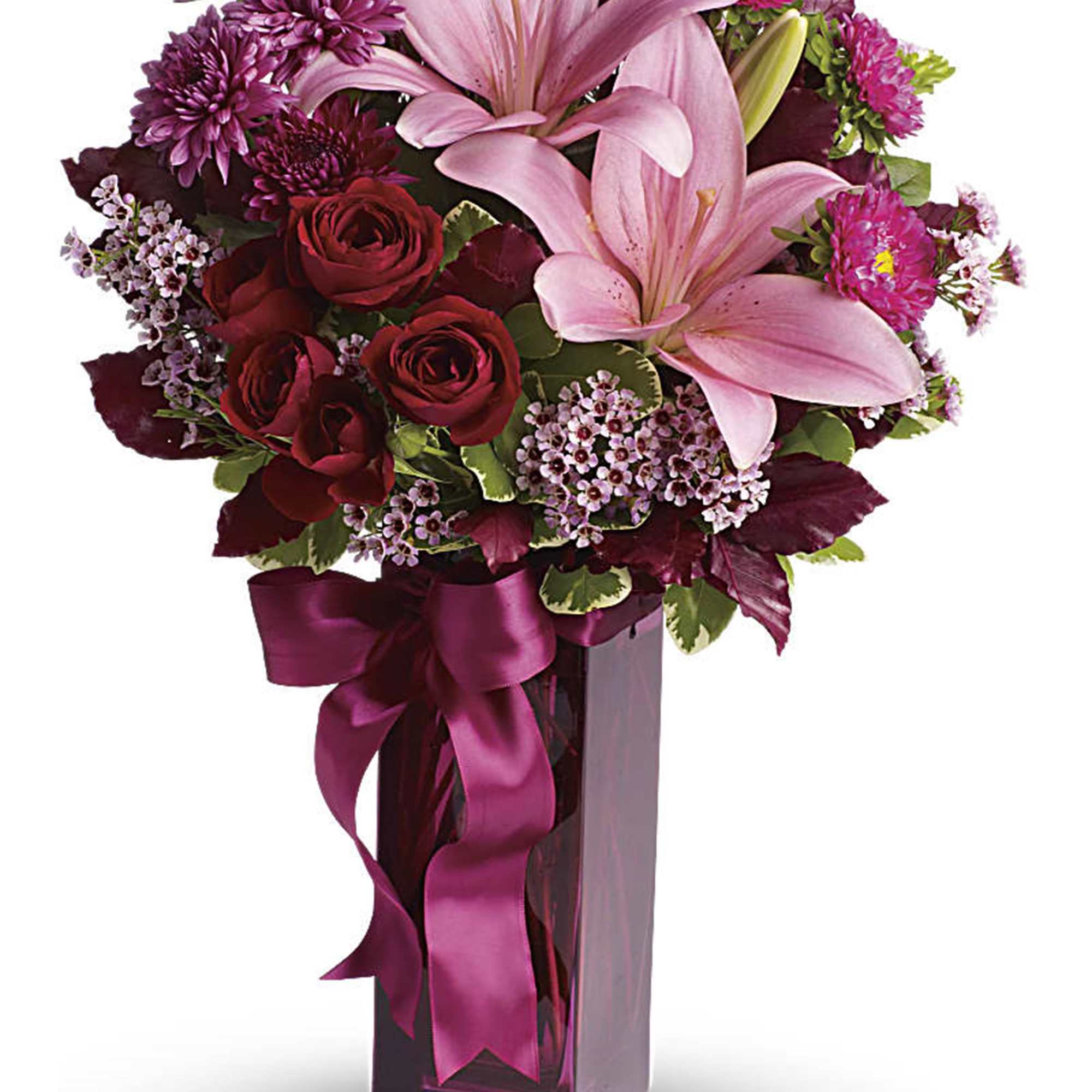 Pink lilies and red roses in a tall glass vase with a ribbon