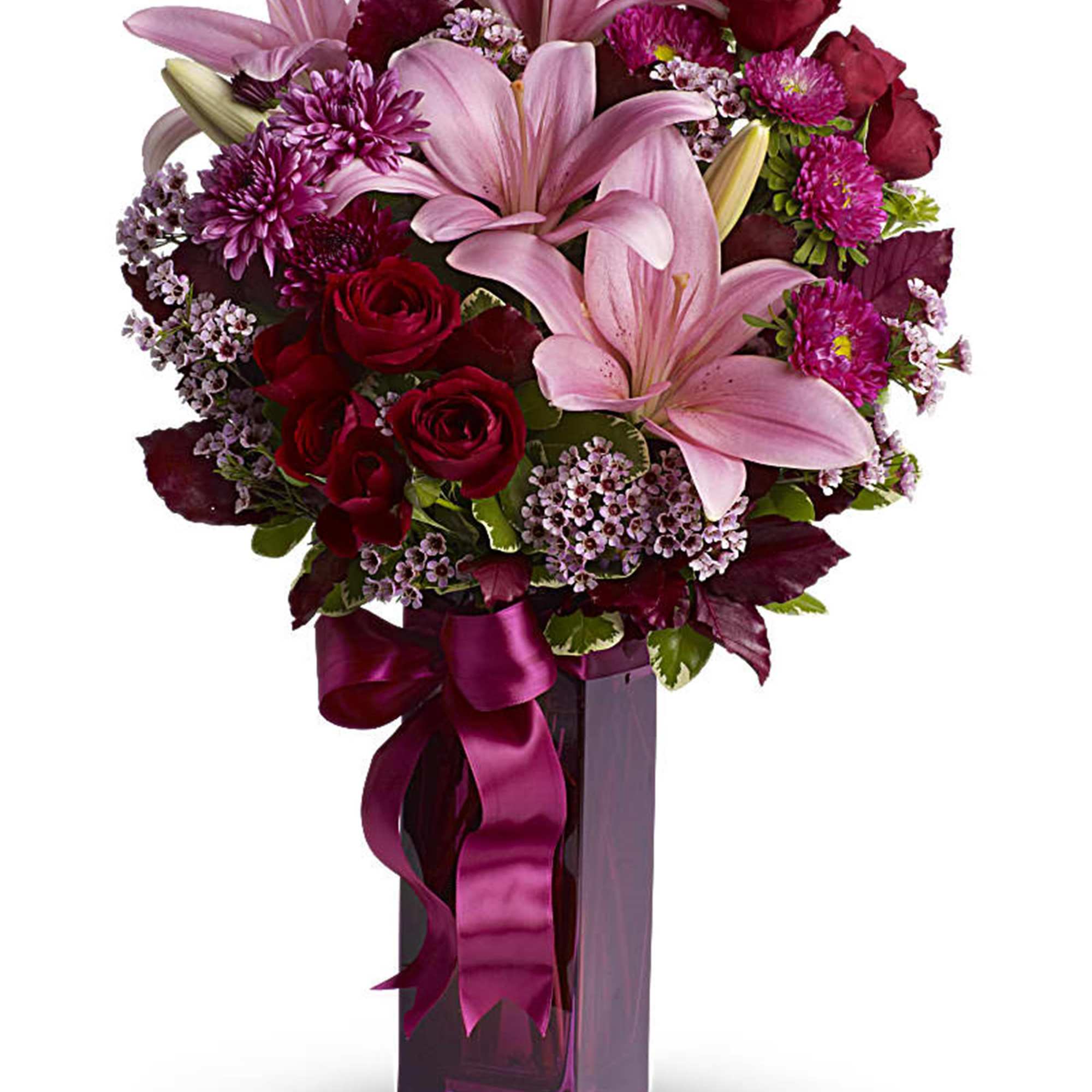 Pink lilies and red roses in a tall purple vase with a ribbon