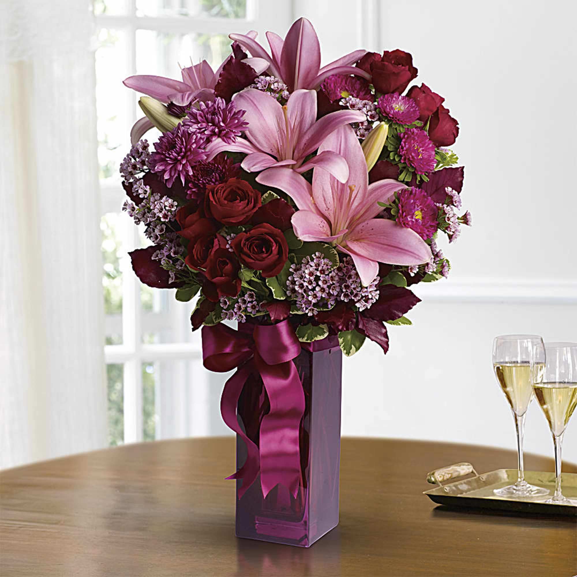 Pink lilies and red roses in a tall purple vase with a ribbon, photo 2 of 2