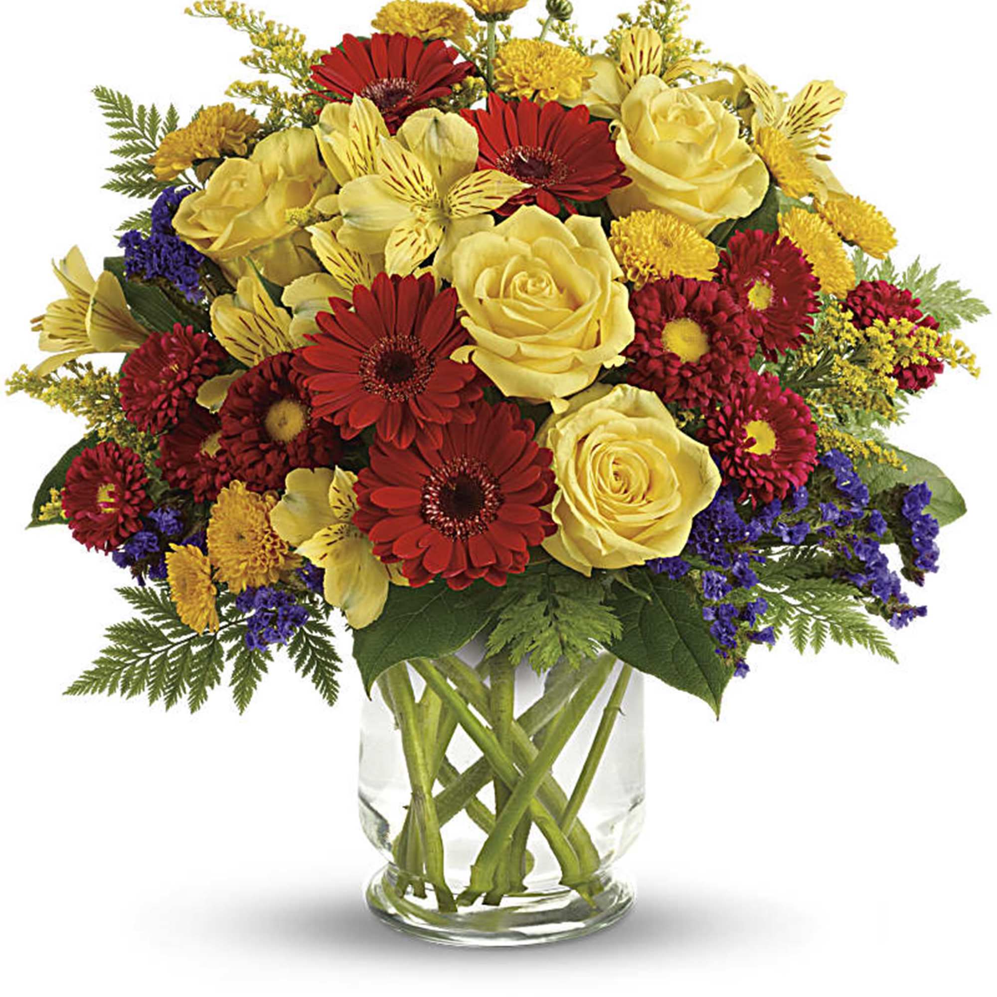 Bouquet of yellow roses, red gerbera daisies, and mixed blooms in a glass vase