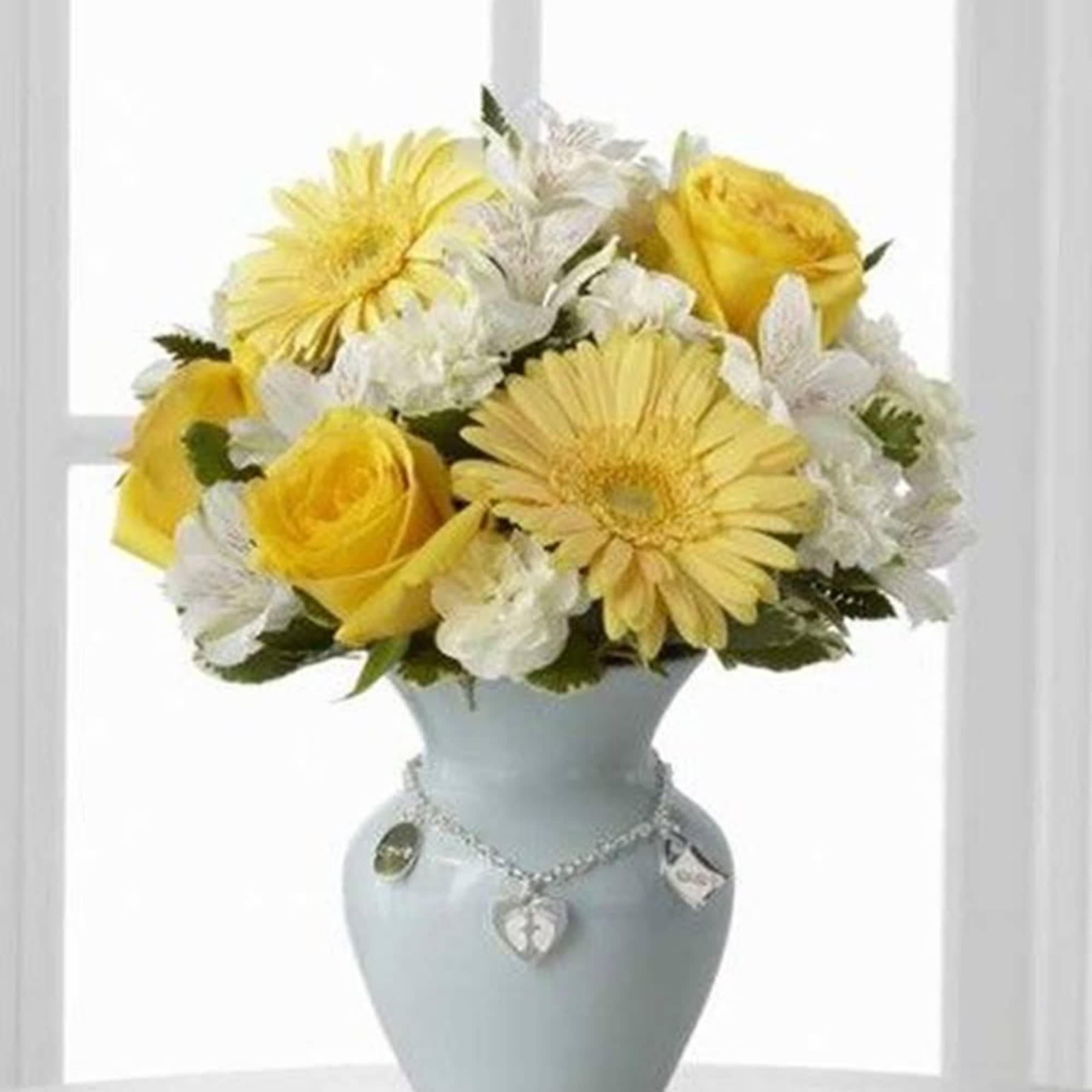 Yellow and white flowers arranged in a pale blue vase