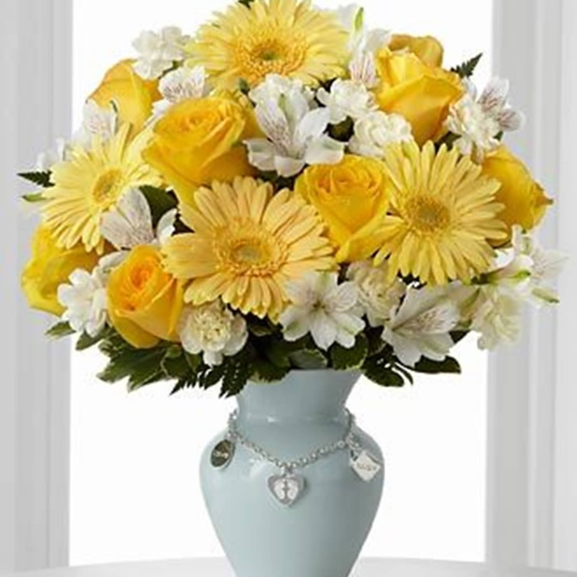 Yellow roses and daisies arranged in a pale blue vase