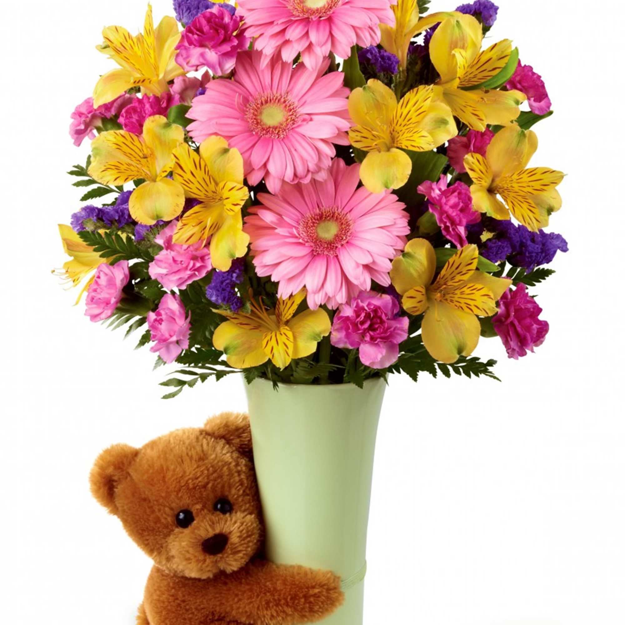 Pink and yellow mixed bouquet in a green vase with a teddy bear
