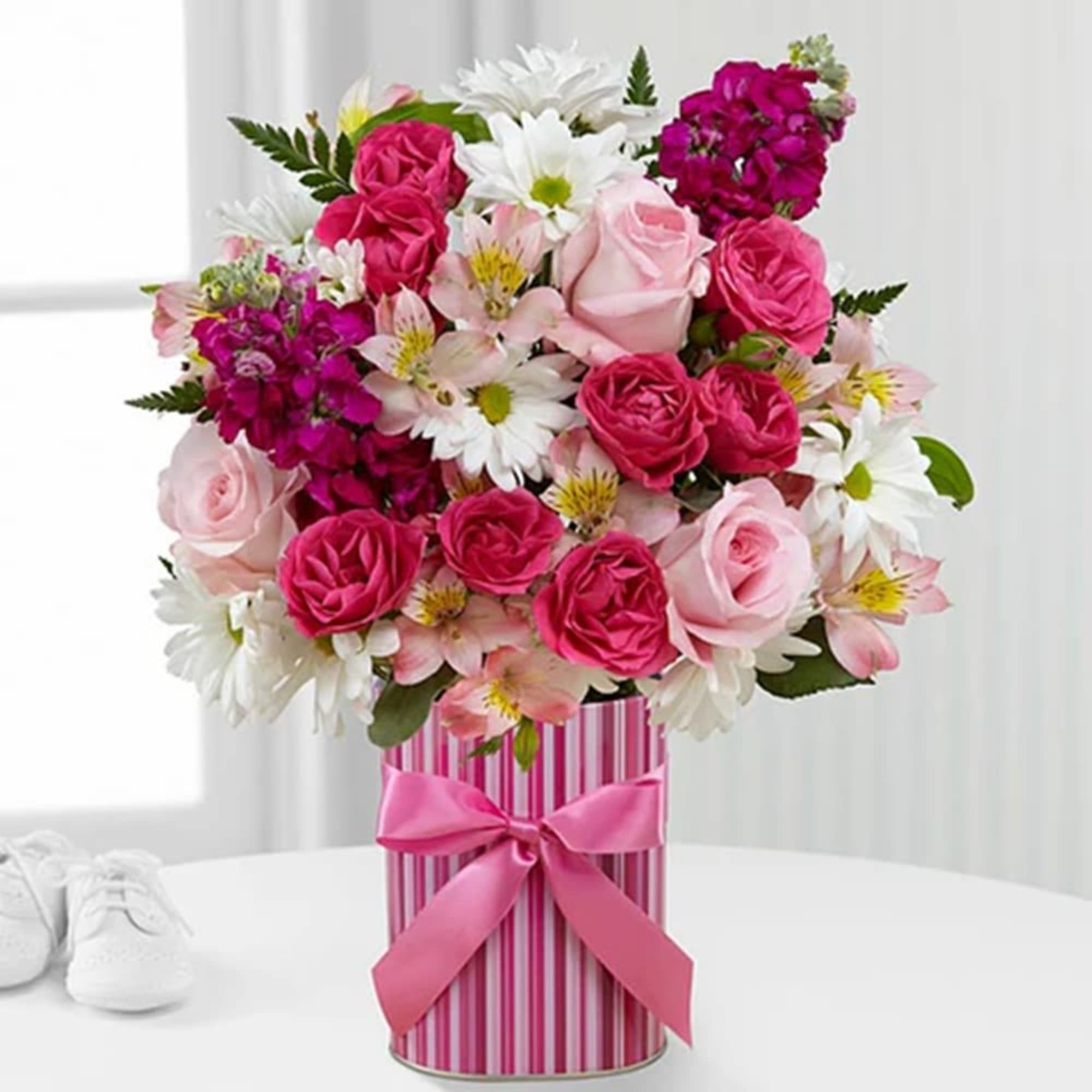 Pink and white mixed flower arrangement in a striped gift box with a ribbon