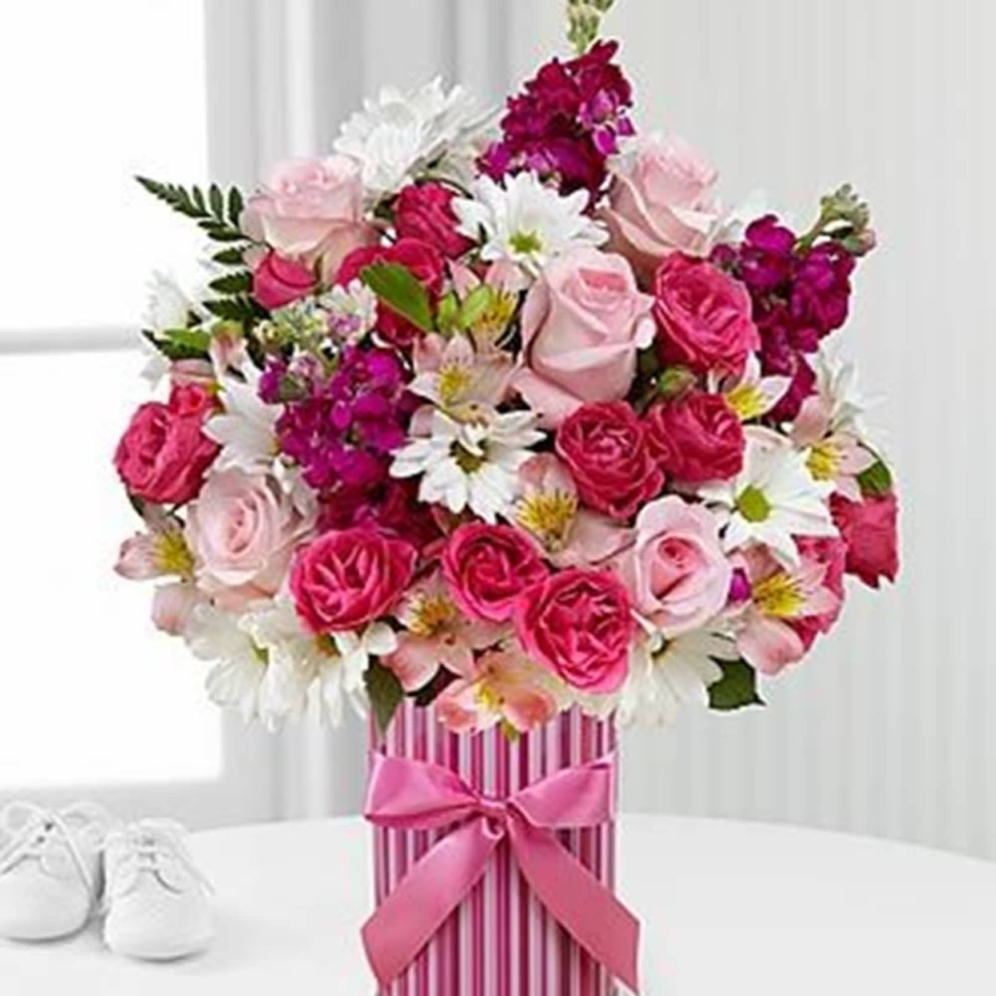 Pink and white rose bouquet in a striped gift box with a ribbon