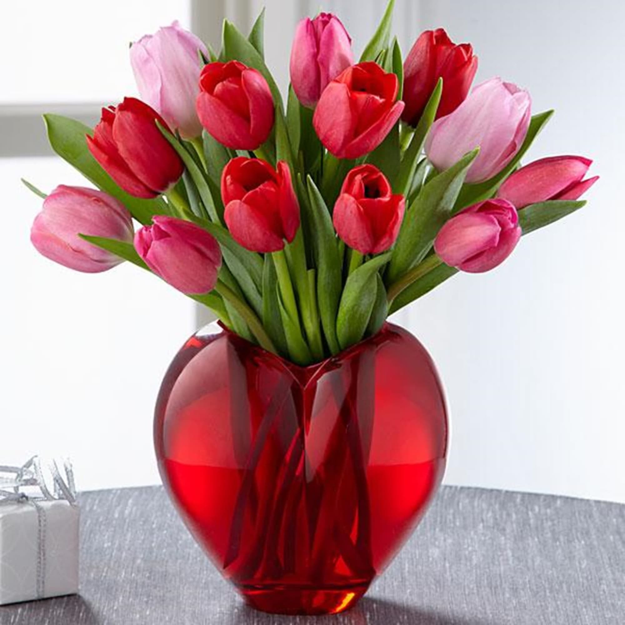 Bouquet of red and pink tulips in a red glass vase