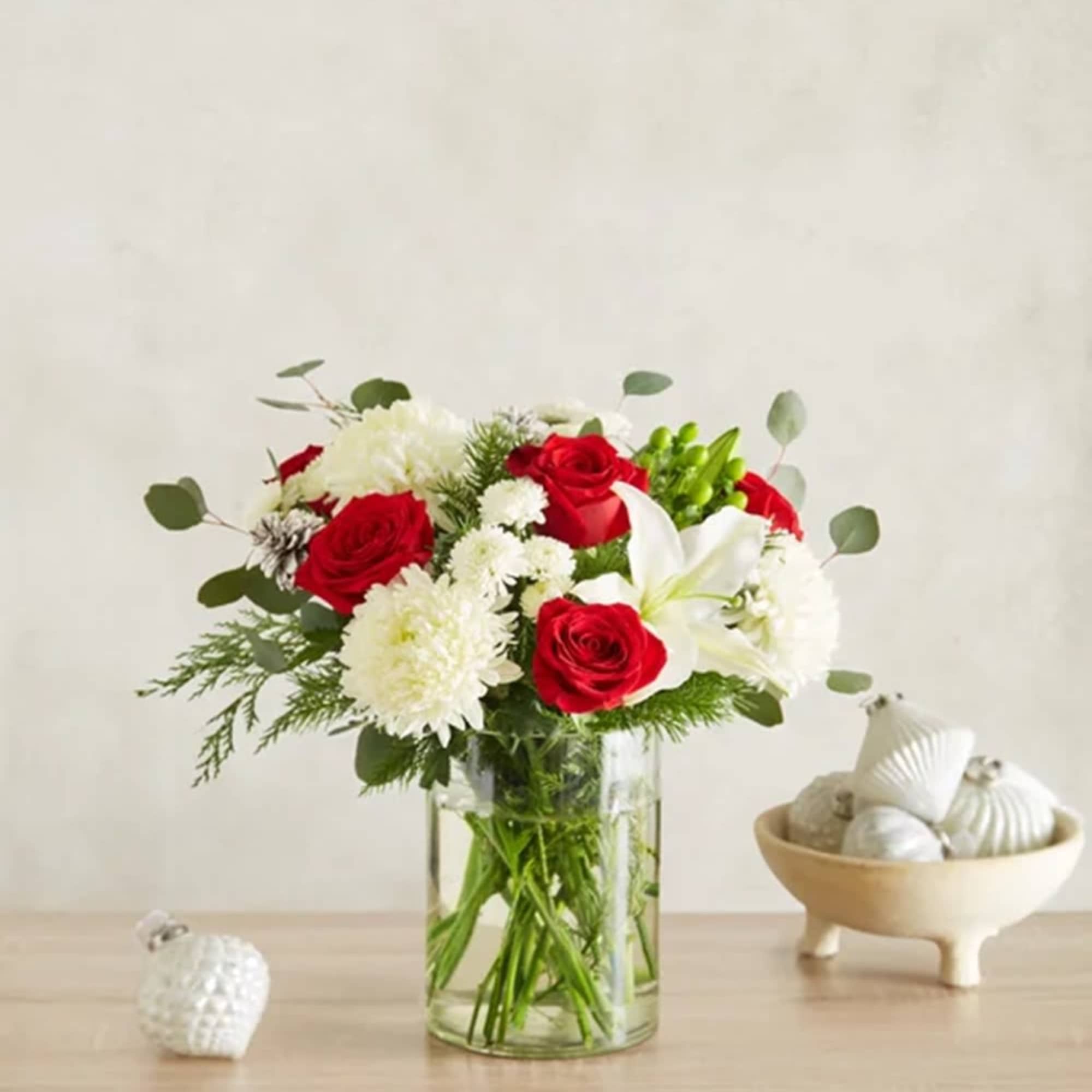 Red roses and white flowers arranged in a clear glass vase
