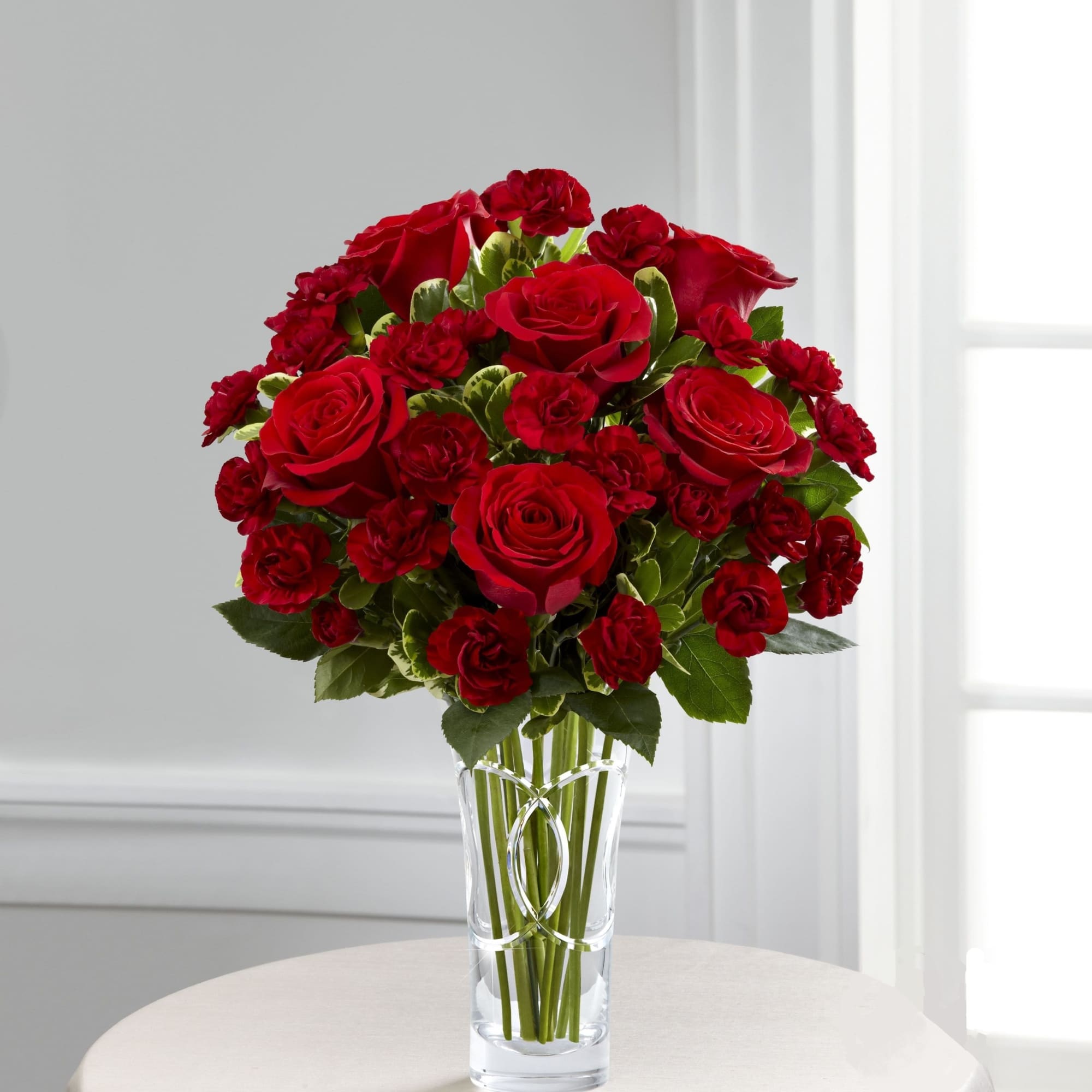 Red roses and spray roses in a clear glass vase