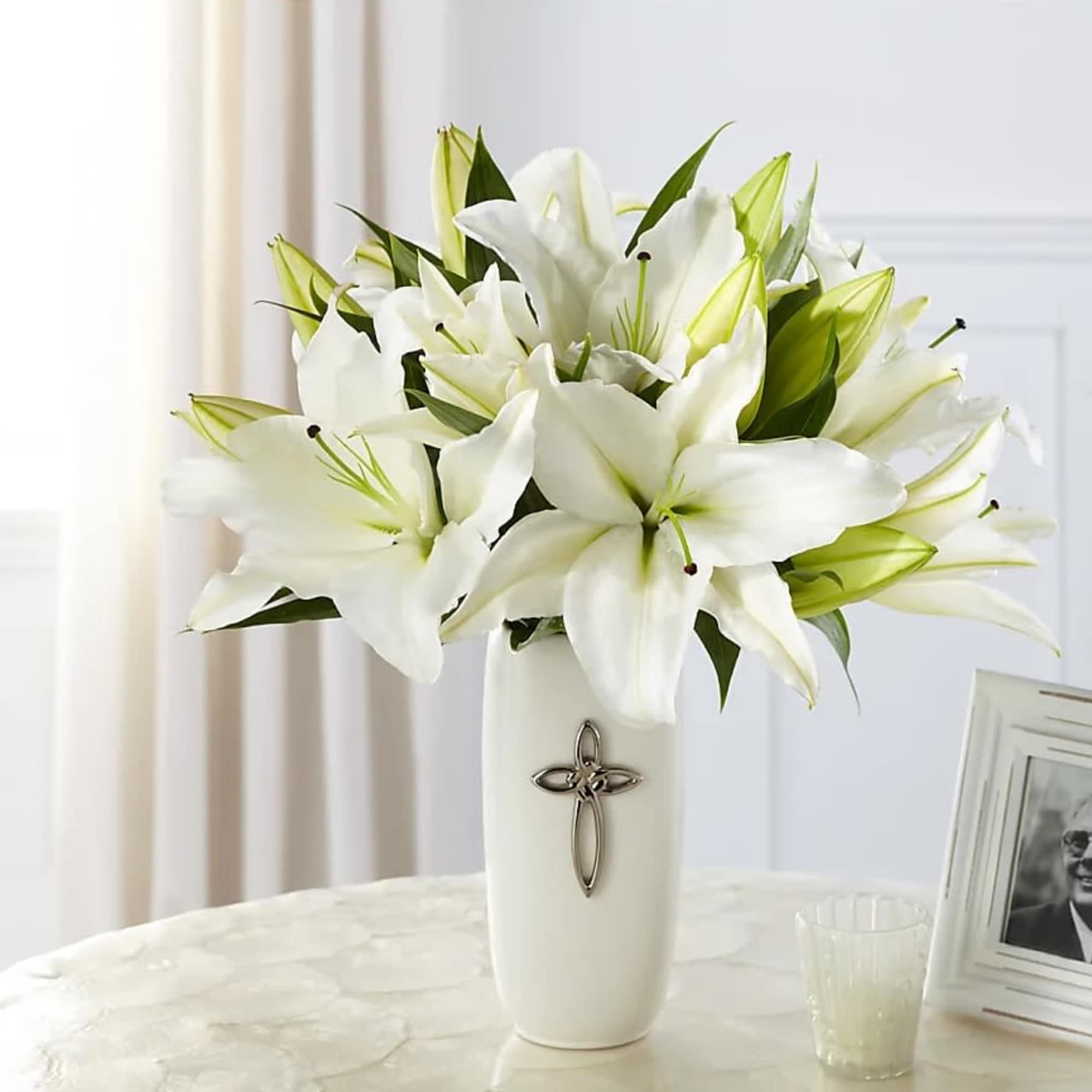 White lilies in a white vase with a cross emblem