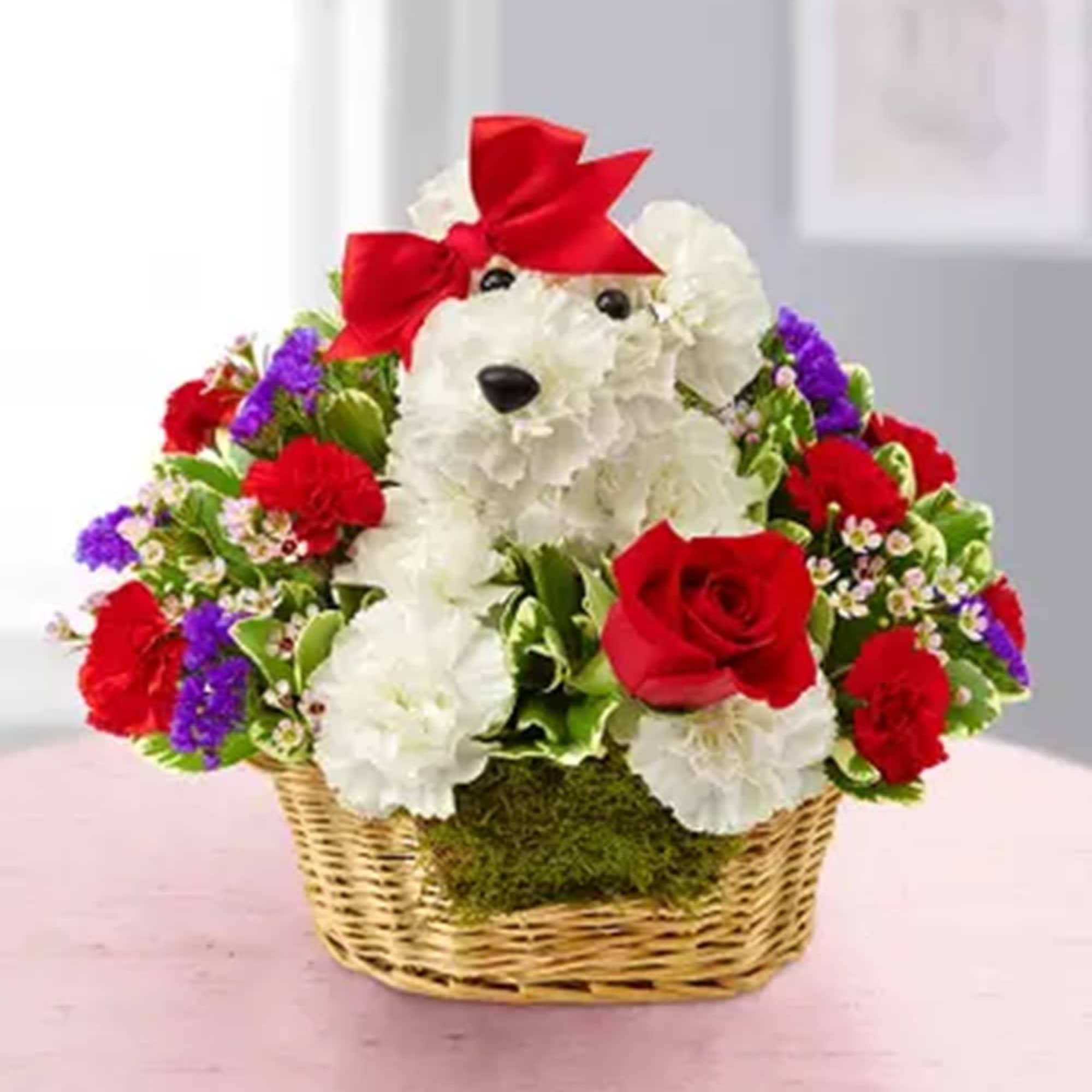 White dog-shaped floral arrangement with red roses and a red bow in a basket