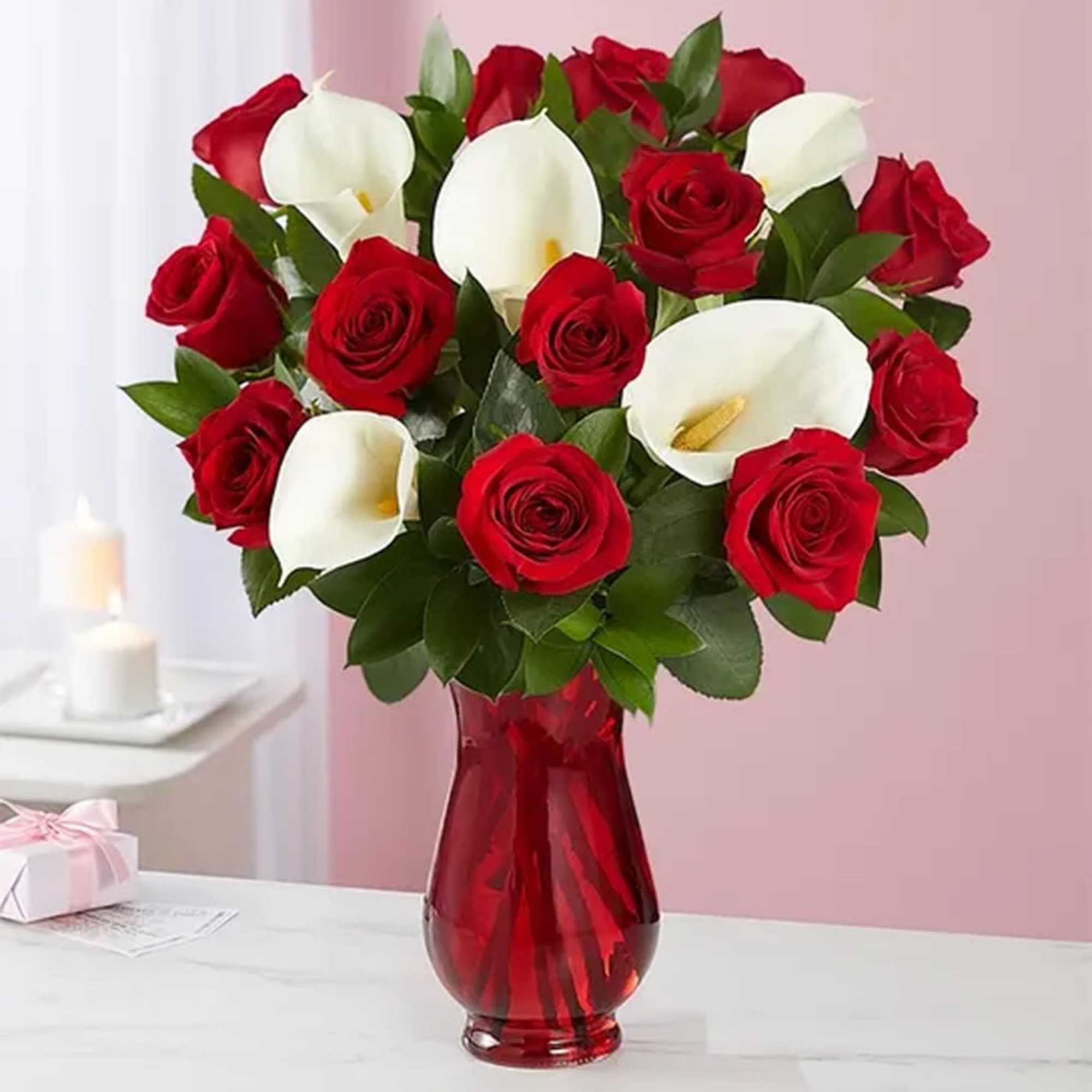 Red roses and white calla lilies in a red glass vase