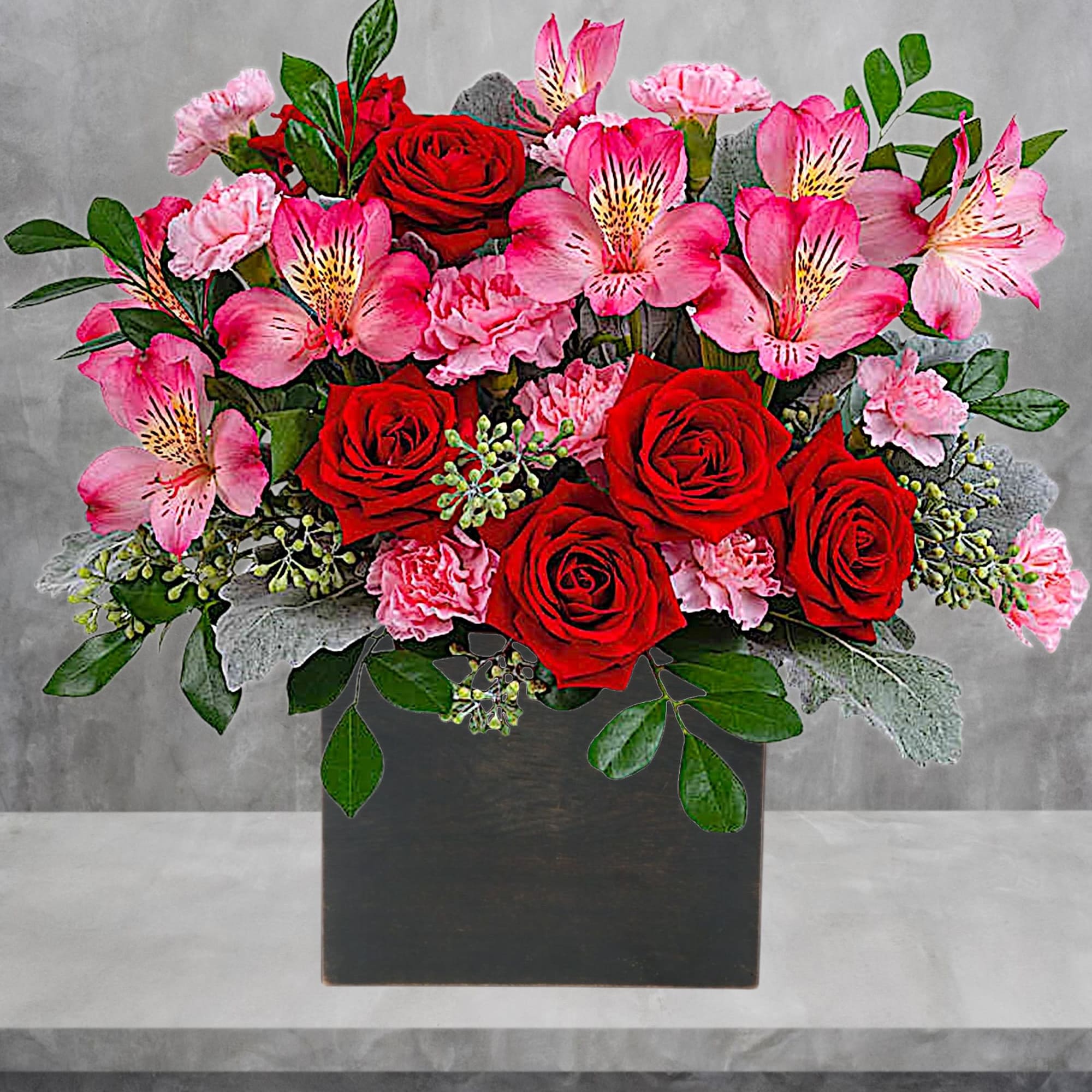 Pink alstroemeria and red roses arranged in a black box