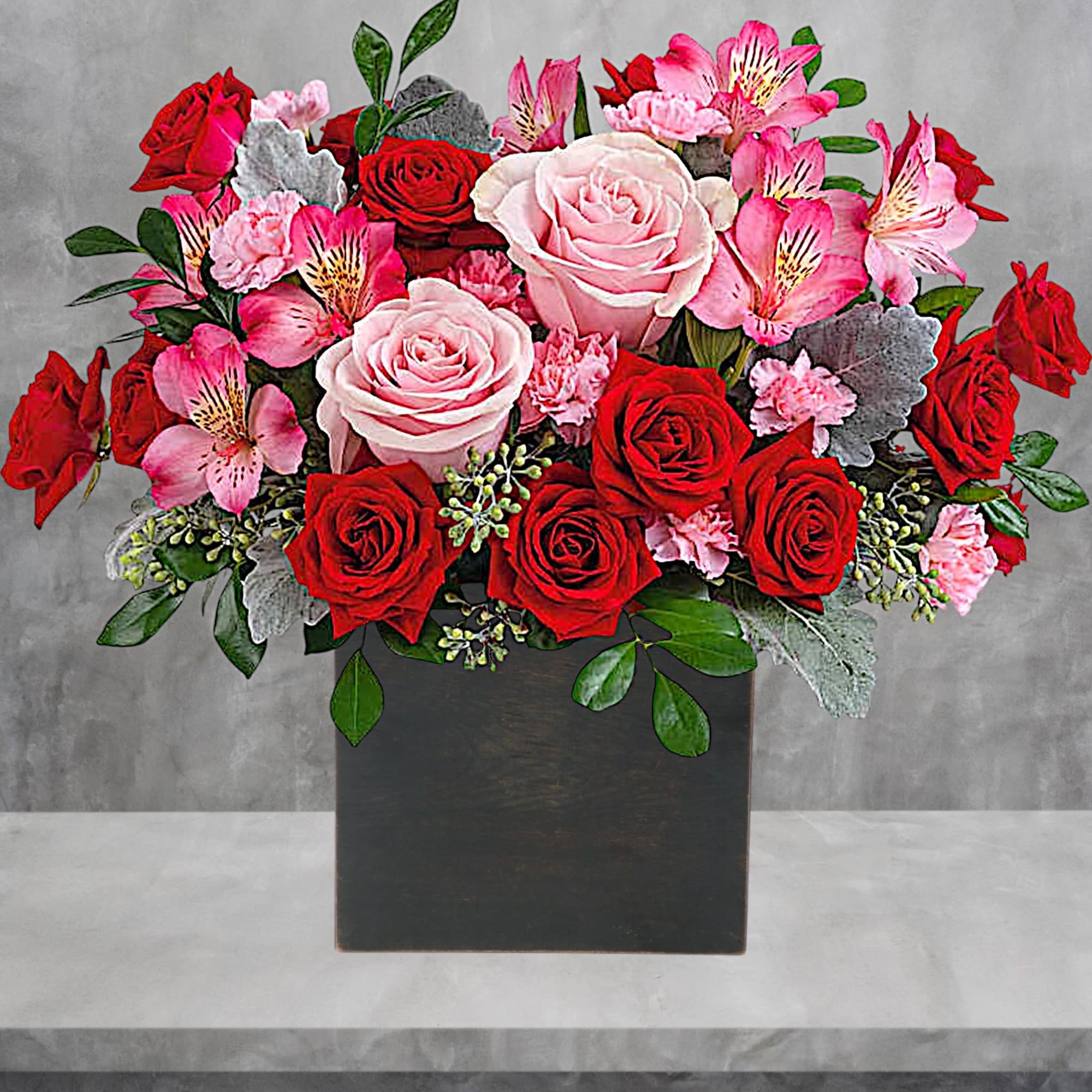 Bouquet of red and pink roses with pink alstroemeria in a black box