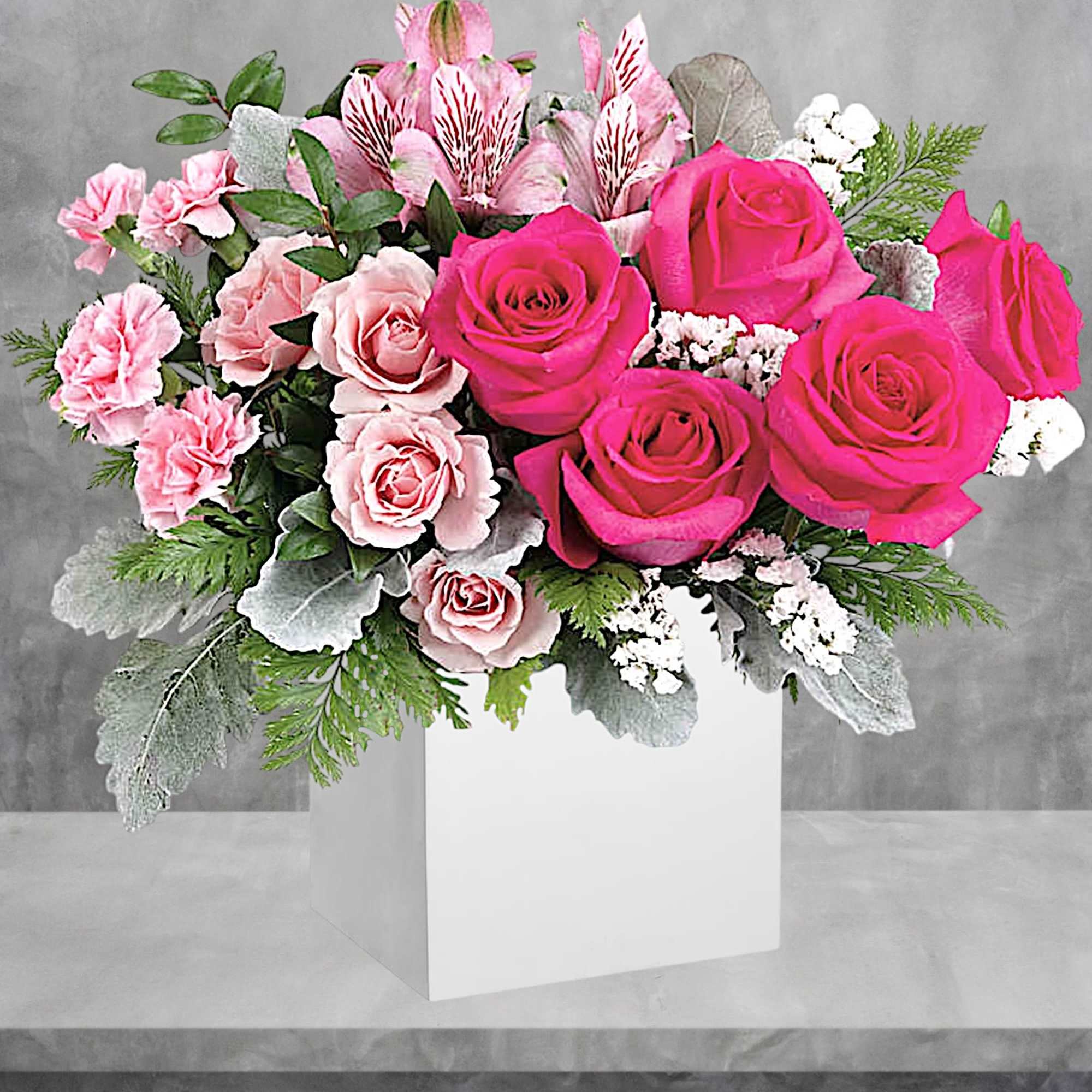 Pink roses and carnations in a white box with greenery