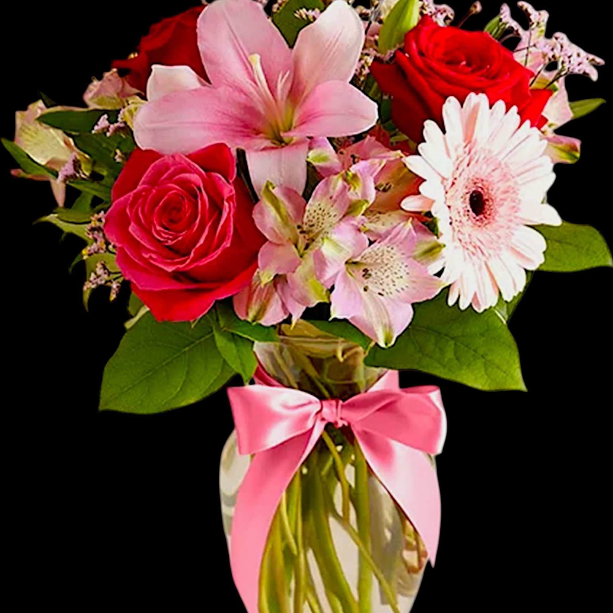 Bouquet of red roses, pink lilies, and white gerbera daisies in a glass vase