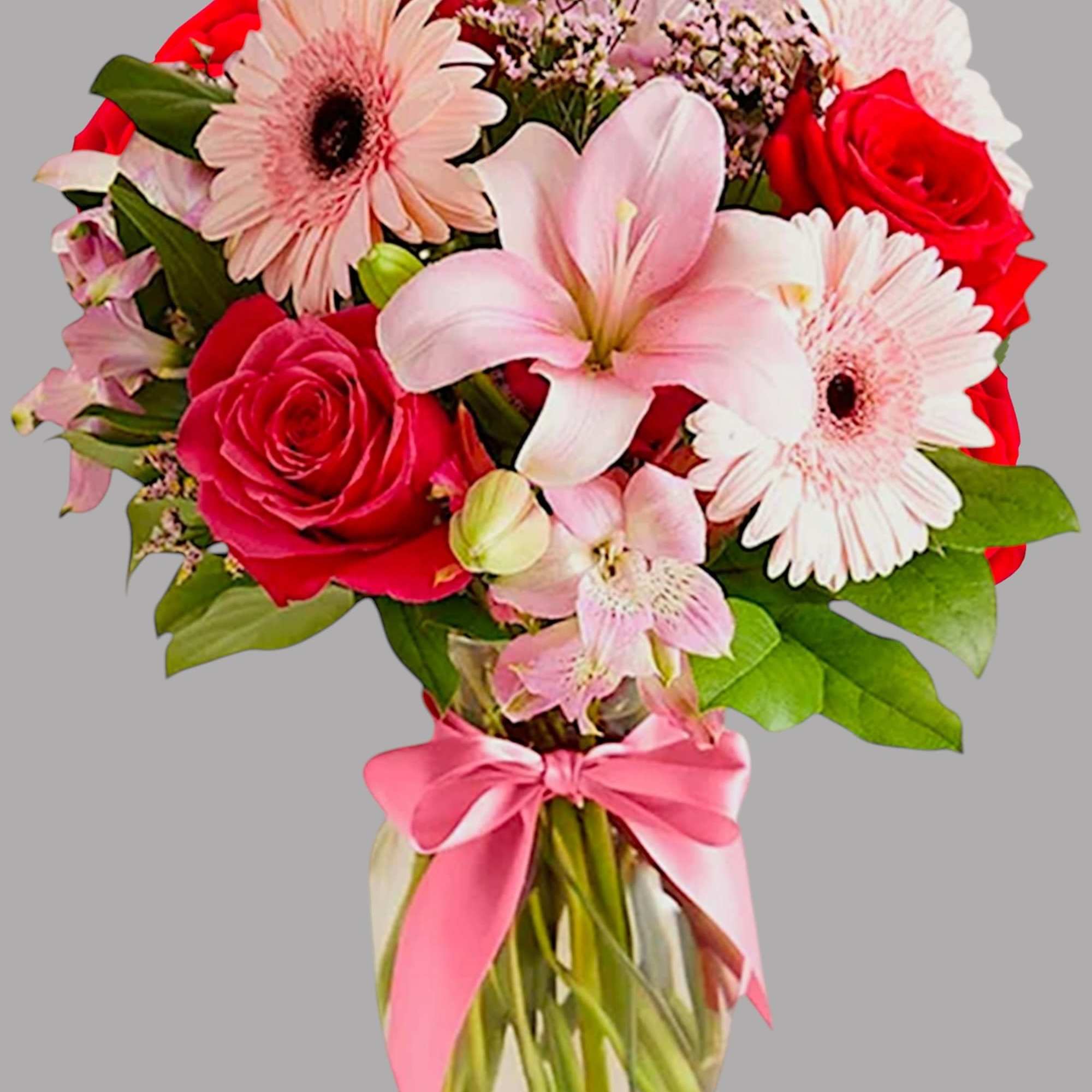 Bouquet of pink and red flowers in a glass vase with a pink ribbon
