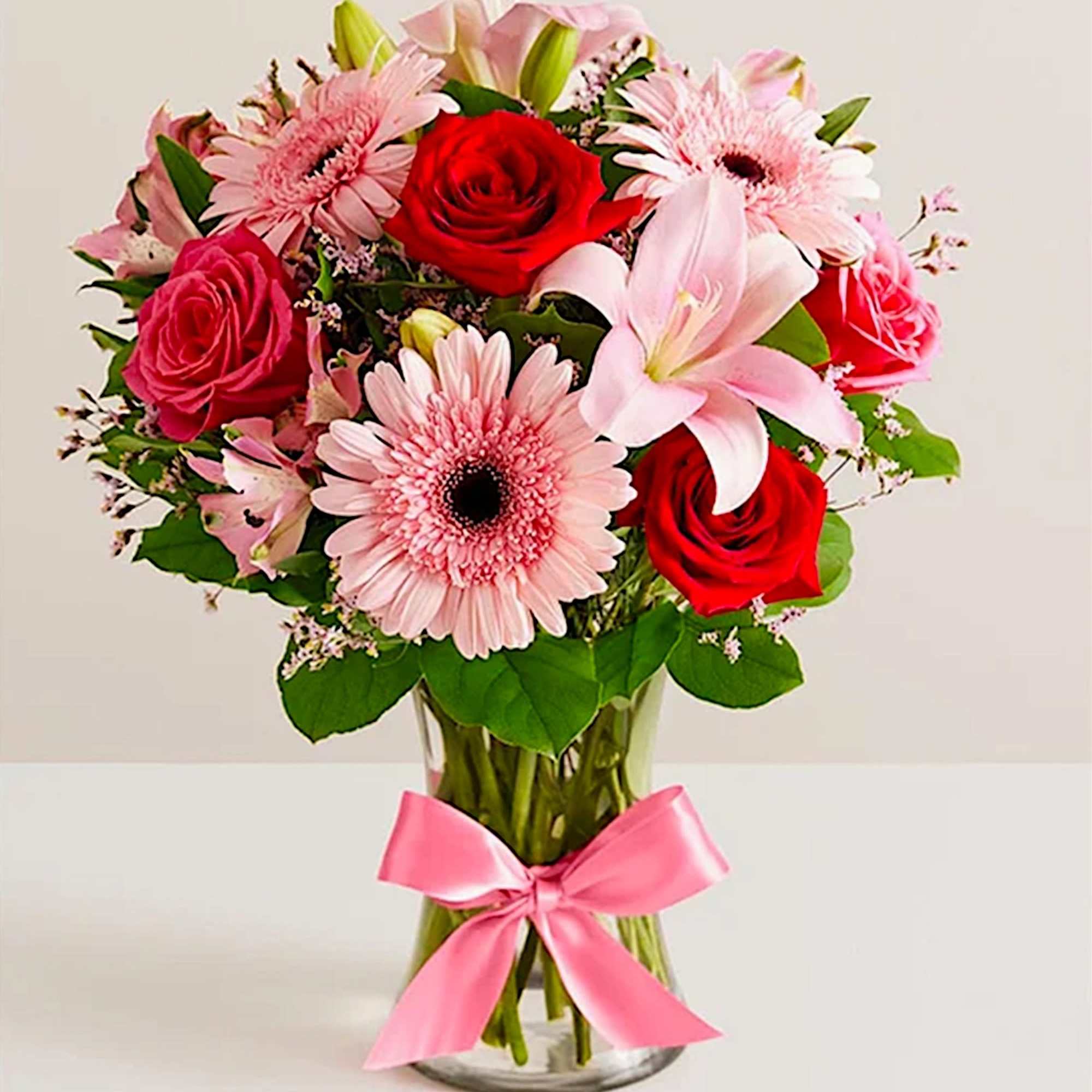 Pink and red mixed bouquet in a glass vase with a pink ribbon