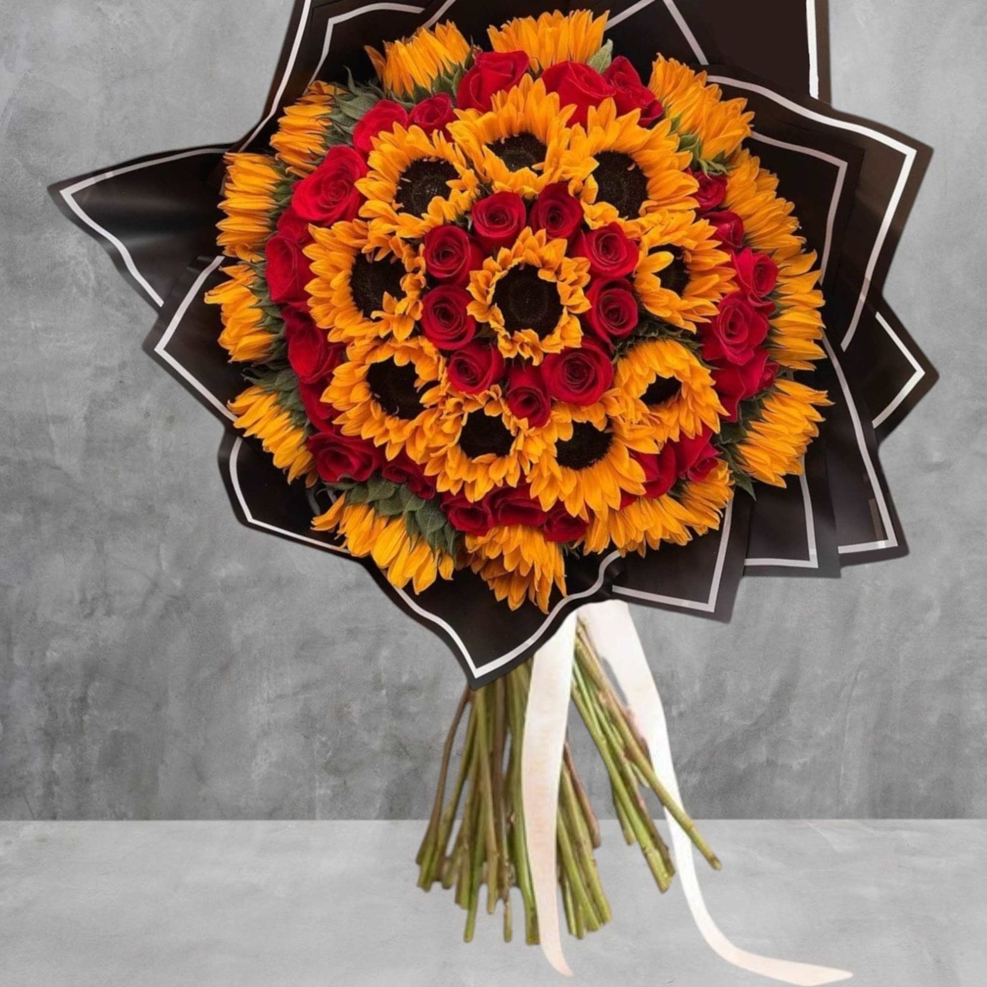 Bouquet of sunflowers and red roses wrapped in black paper