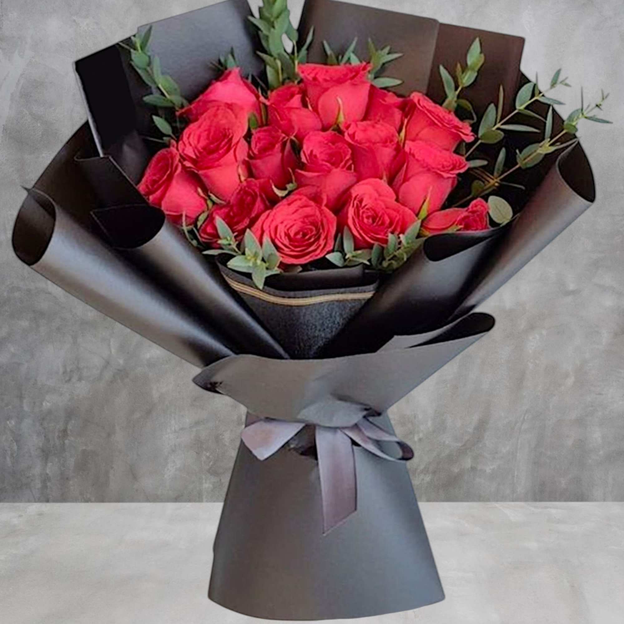 Bouquet of bright pink roses wrapped in black paper