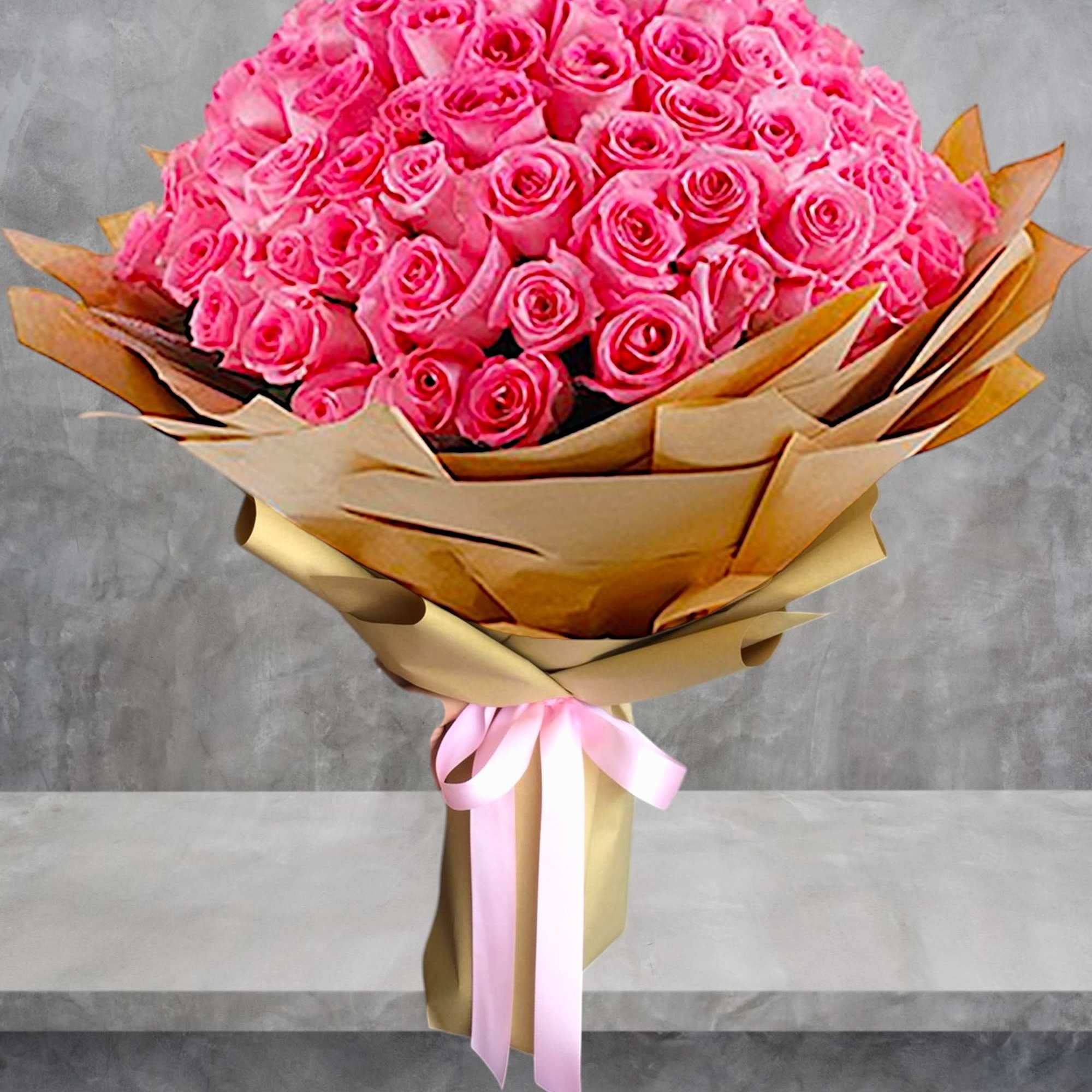 Large bouquet of bright pink roses wrapped in tan paper with a pink ribbon