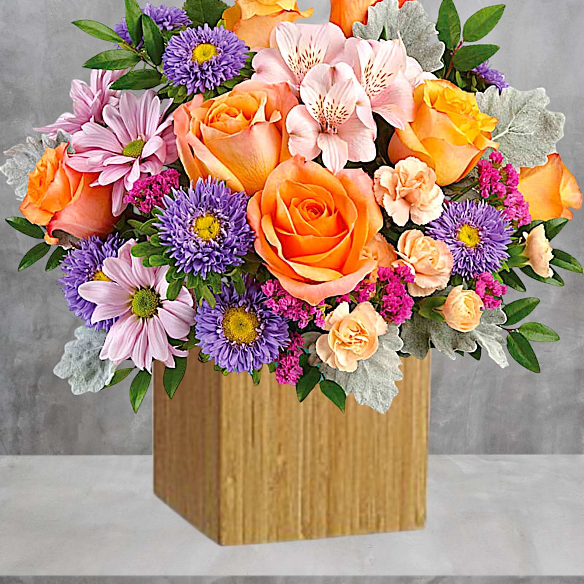 Bouquet of orange roses, pink alstroemeria, and purple daisies in a wooden box
