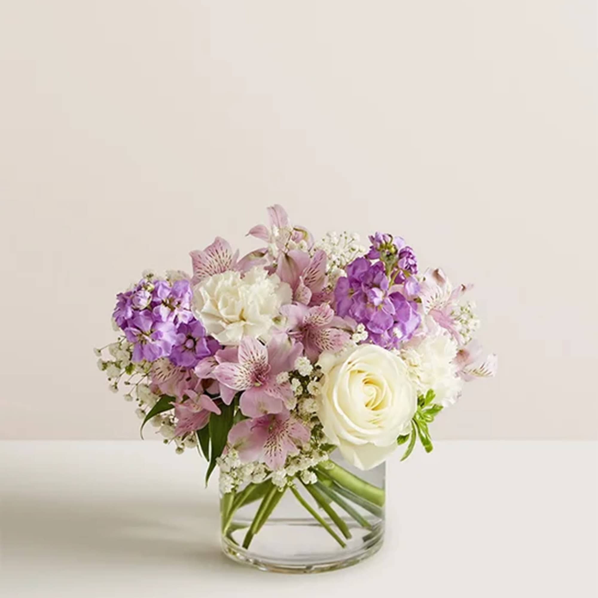 Bouquet of white roses and pink-purple flowers in a clear glass vase