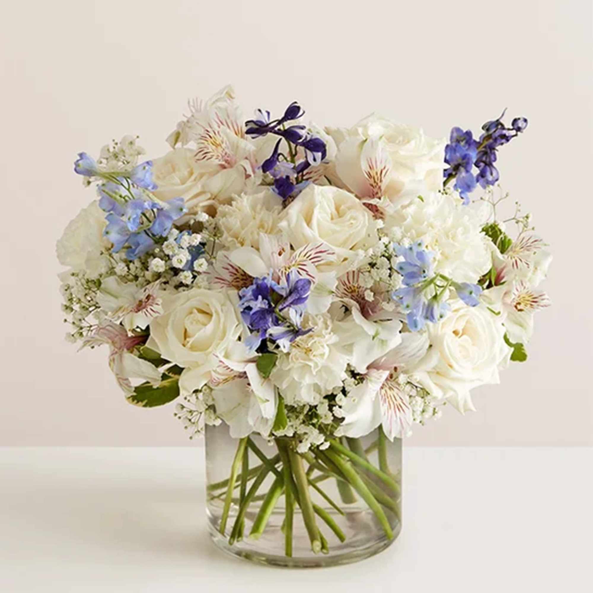 White and blue mixed bouquet in a clear glass vase