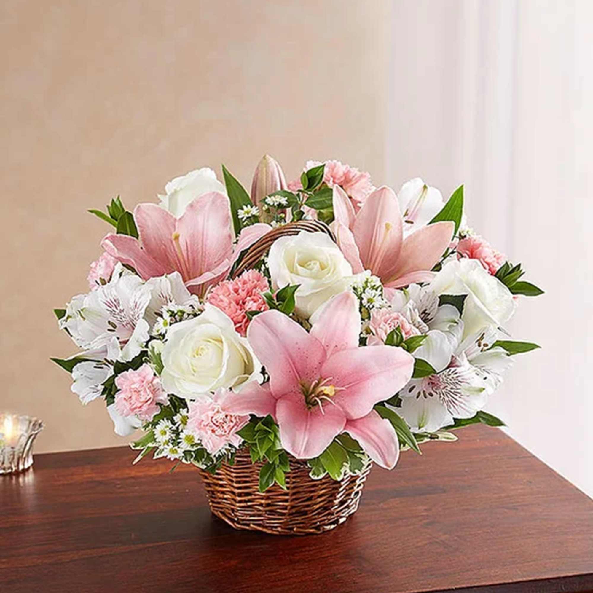 Pink and white lilies and roses arranged in a wicker basket