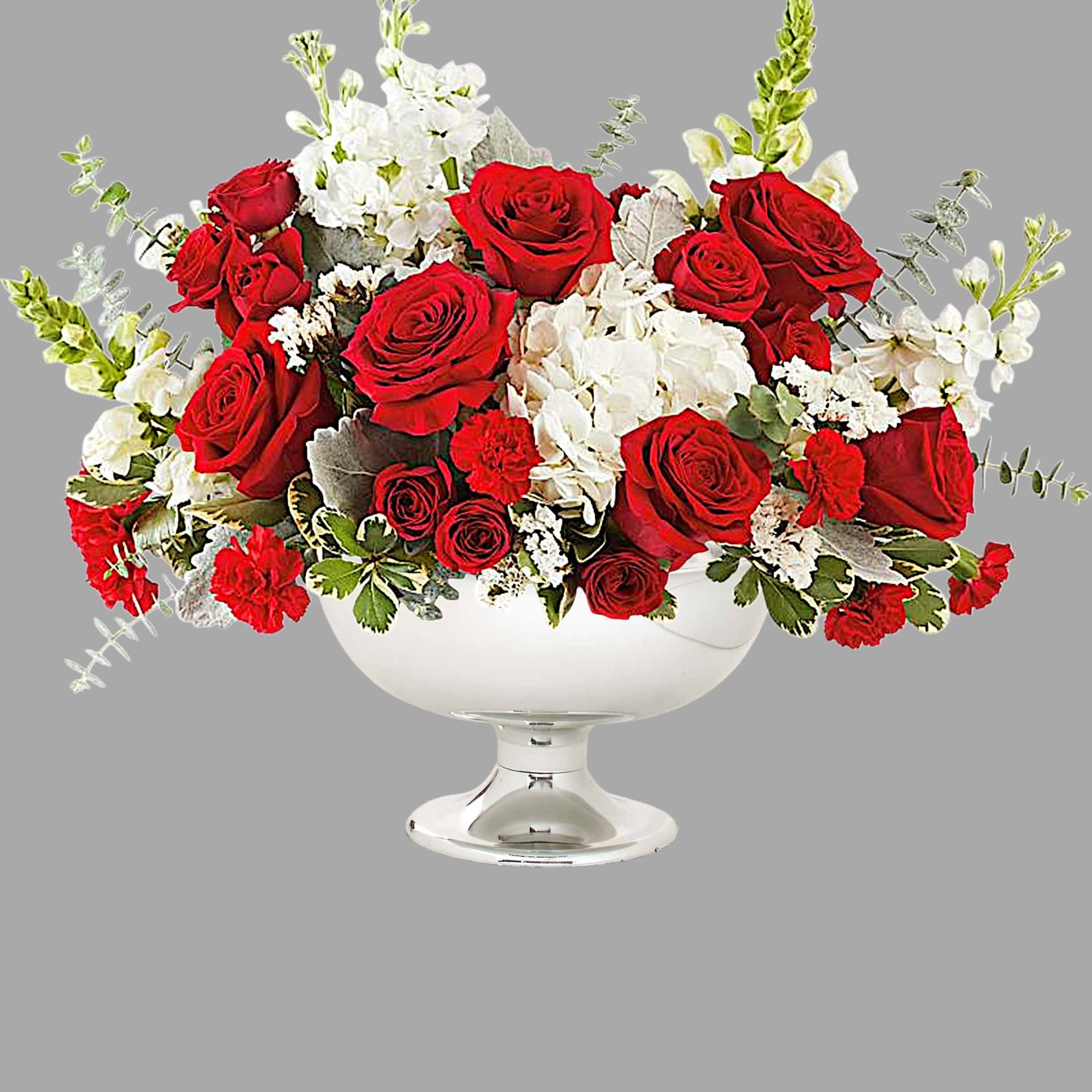 Red roses and white flowers arranged in a white pedestal vase