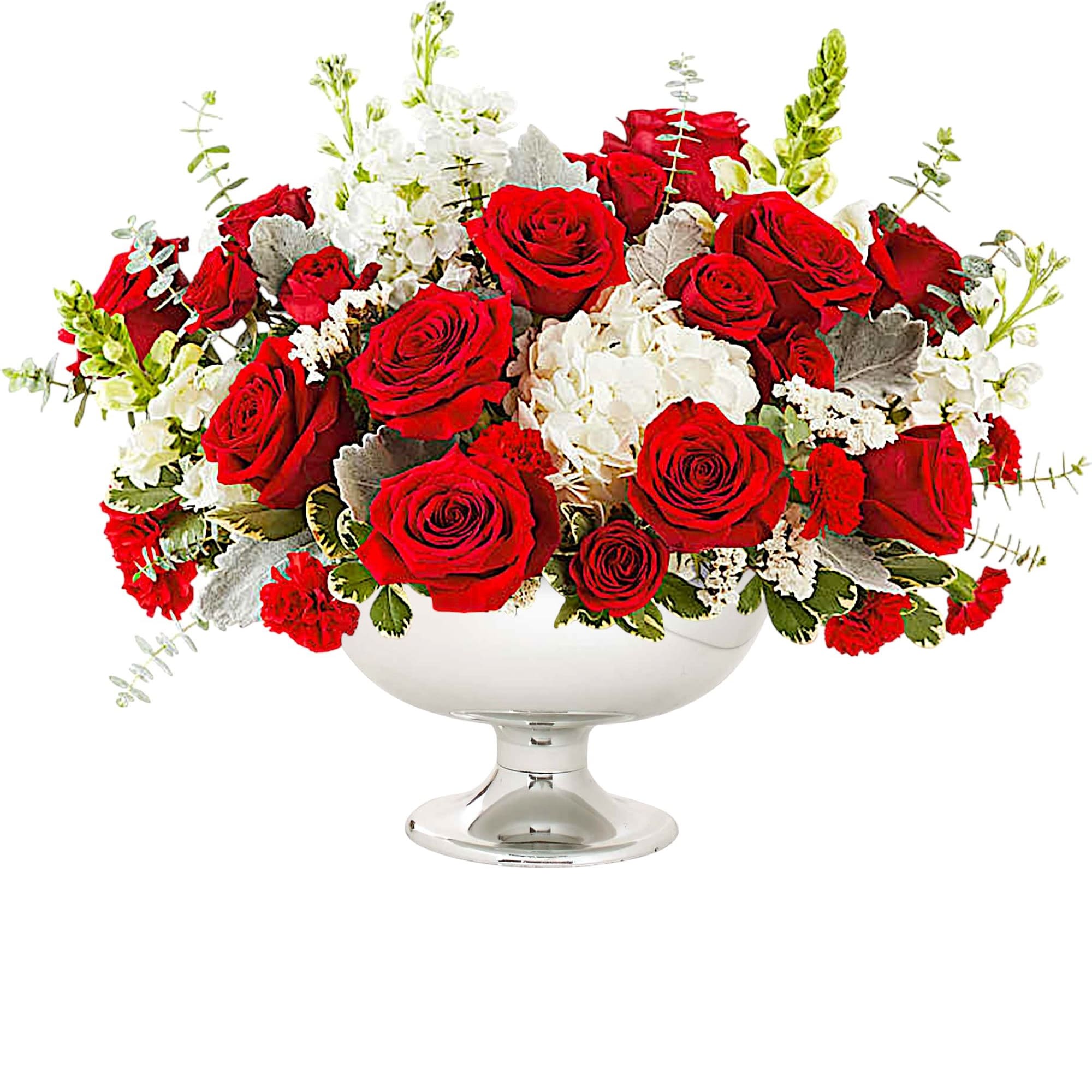 Red roses and white flowers arranged in a clear pedestal vase