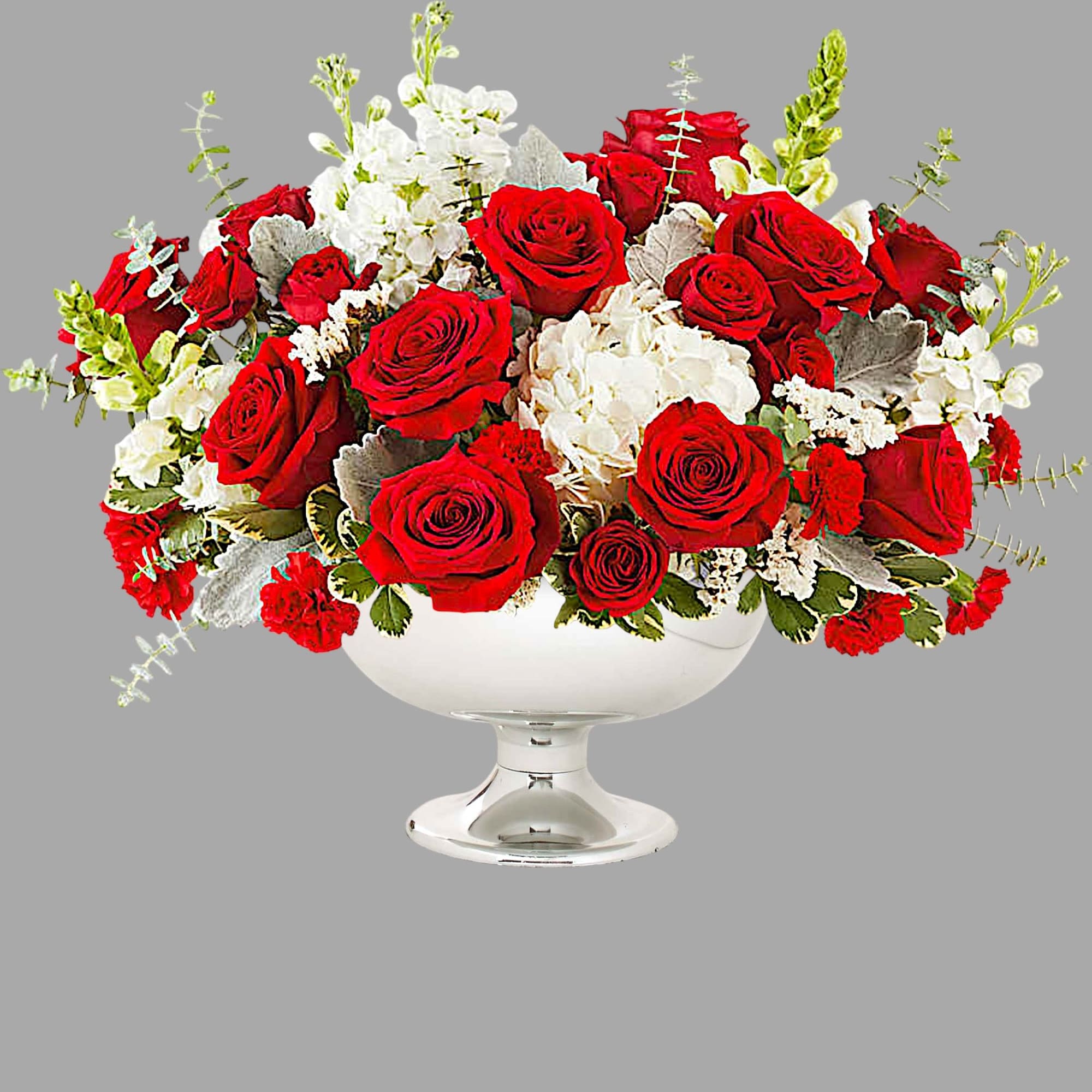 Red roses and white flowers arranged in a white pedestal bowl