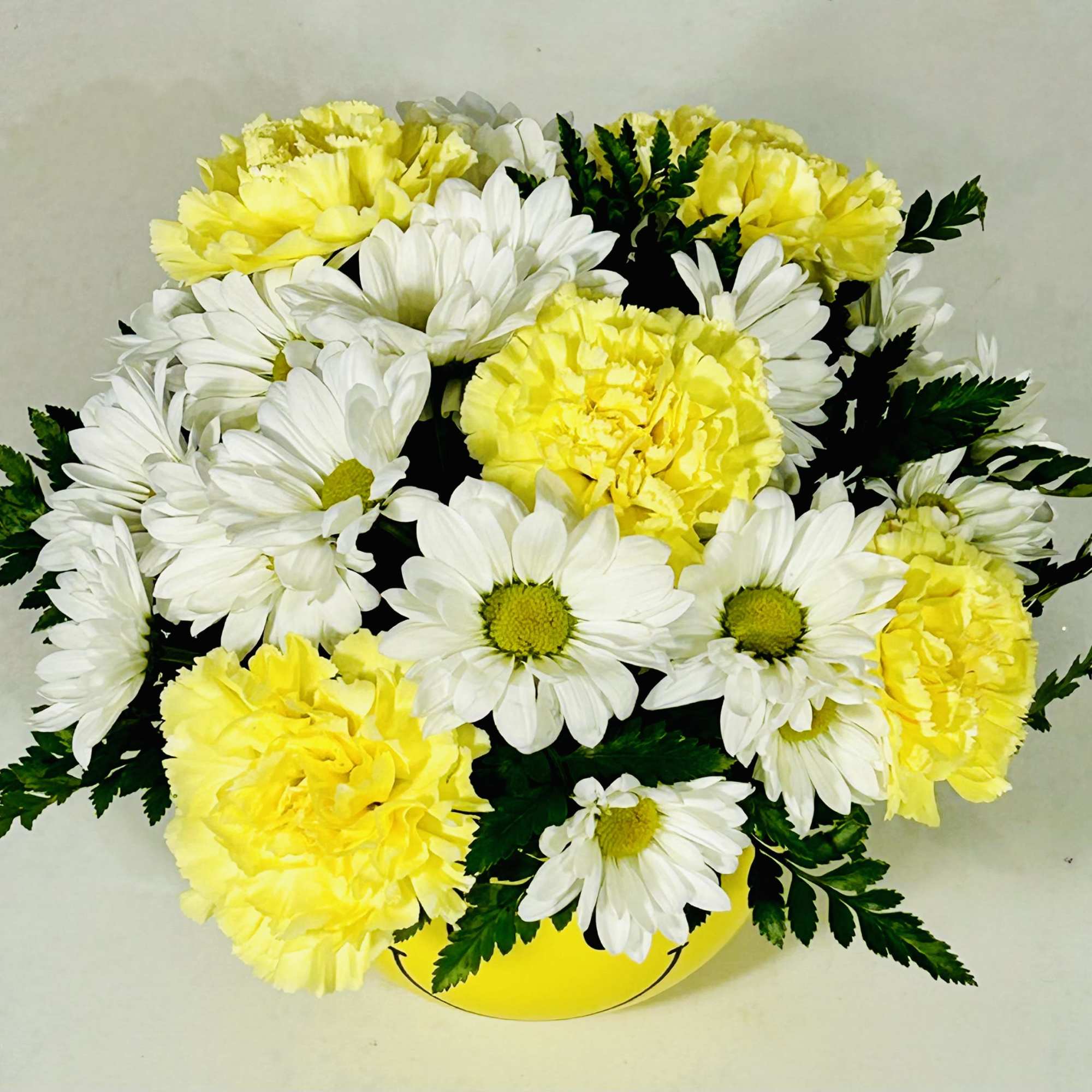 Yellow carnations and white daisies in a yellow container
