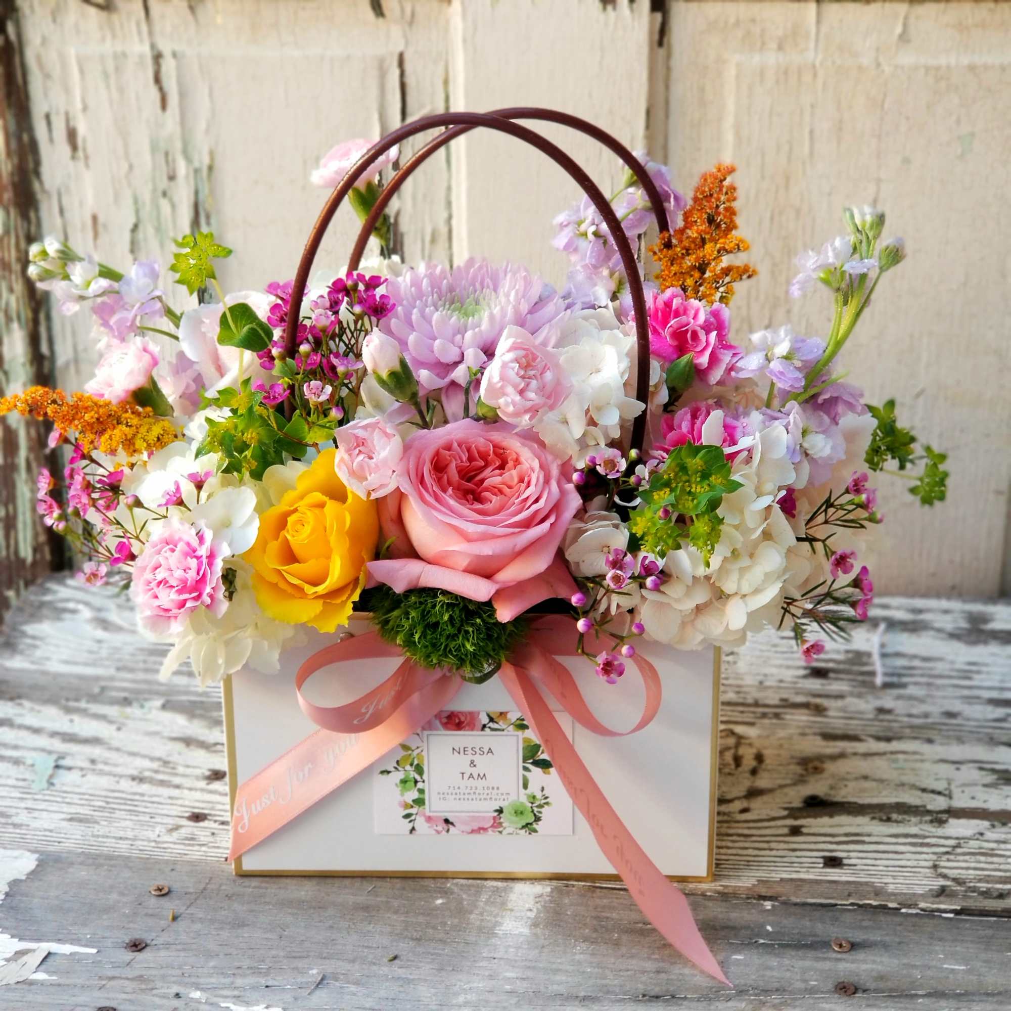 Mixed pastel flower arrangement in a white gift box with pink ribbon handles