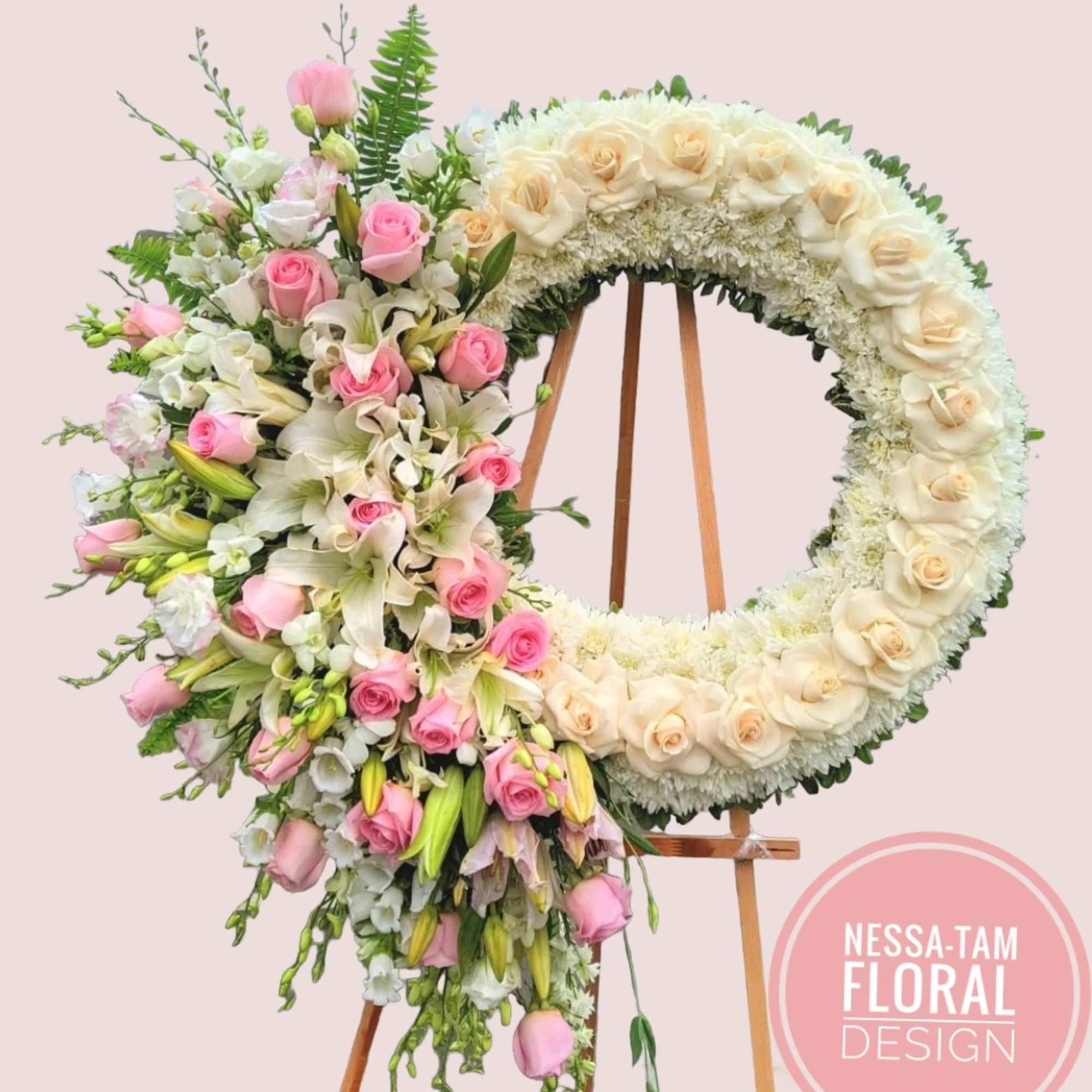 Floral wreath on an easel with pink and cream roses and lilies