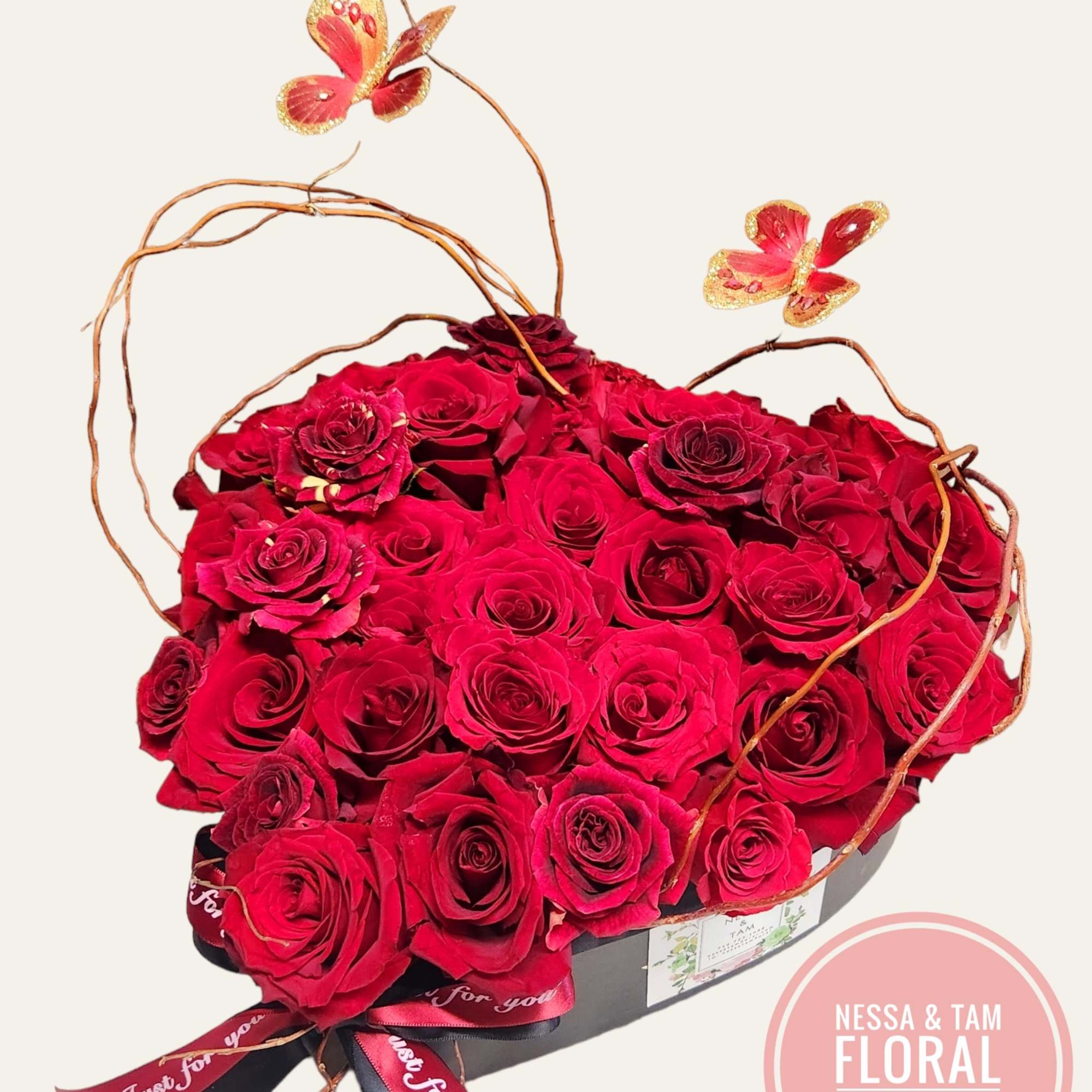 Heart-shaped box filled with red roses and butterfly picks
