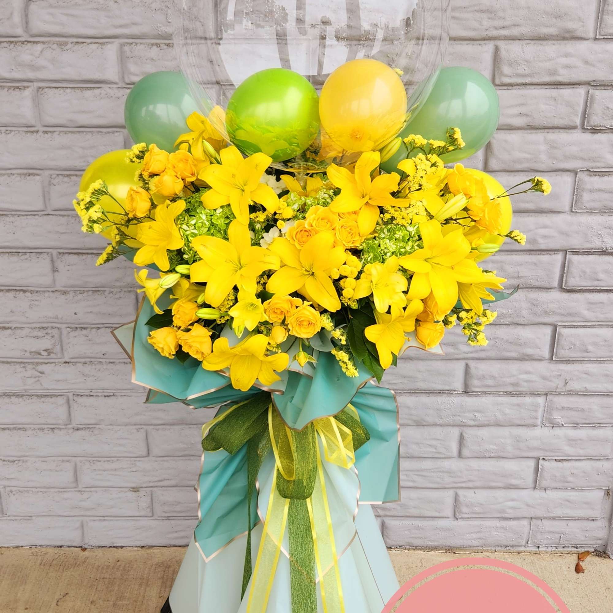Yellow floral standing arrangement with balloons and ribbon wrap
