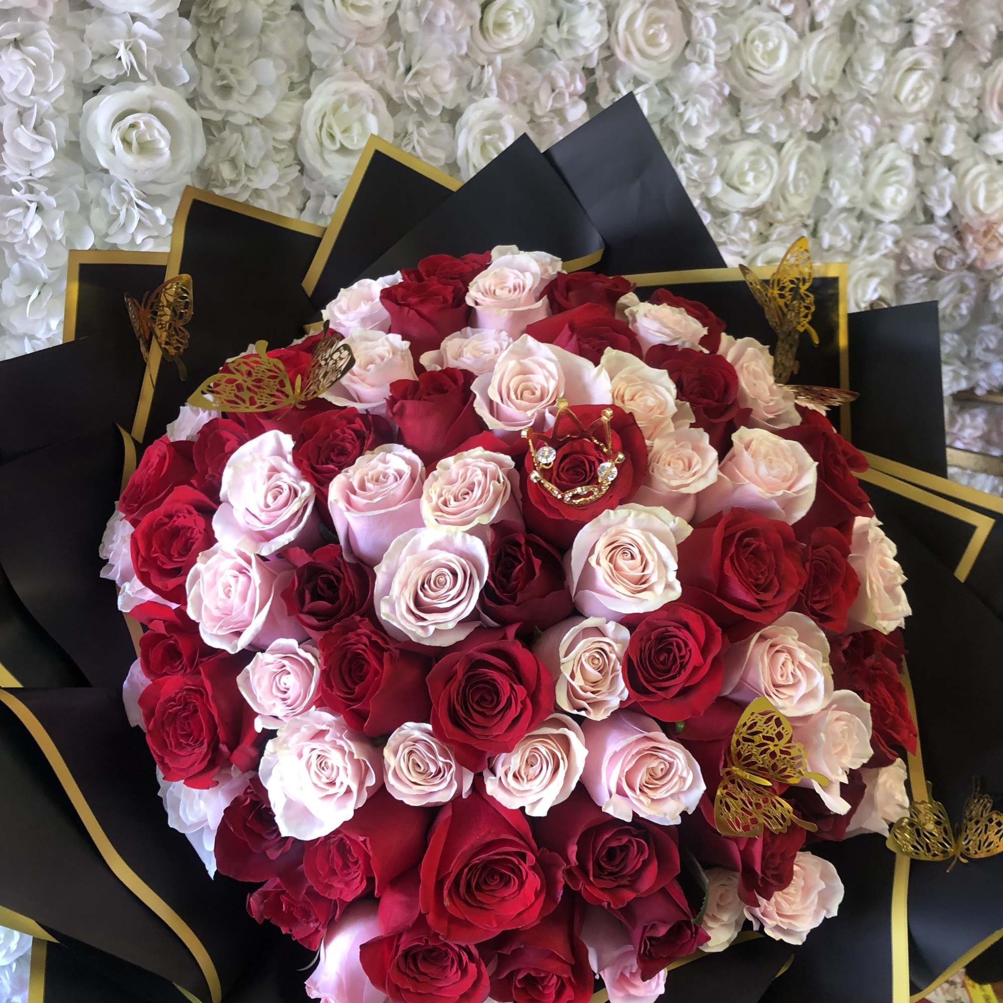 Bouquet of red, pink, and white roses wrapped in black paper with gold trim