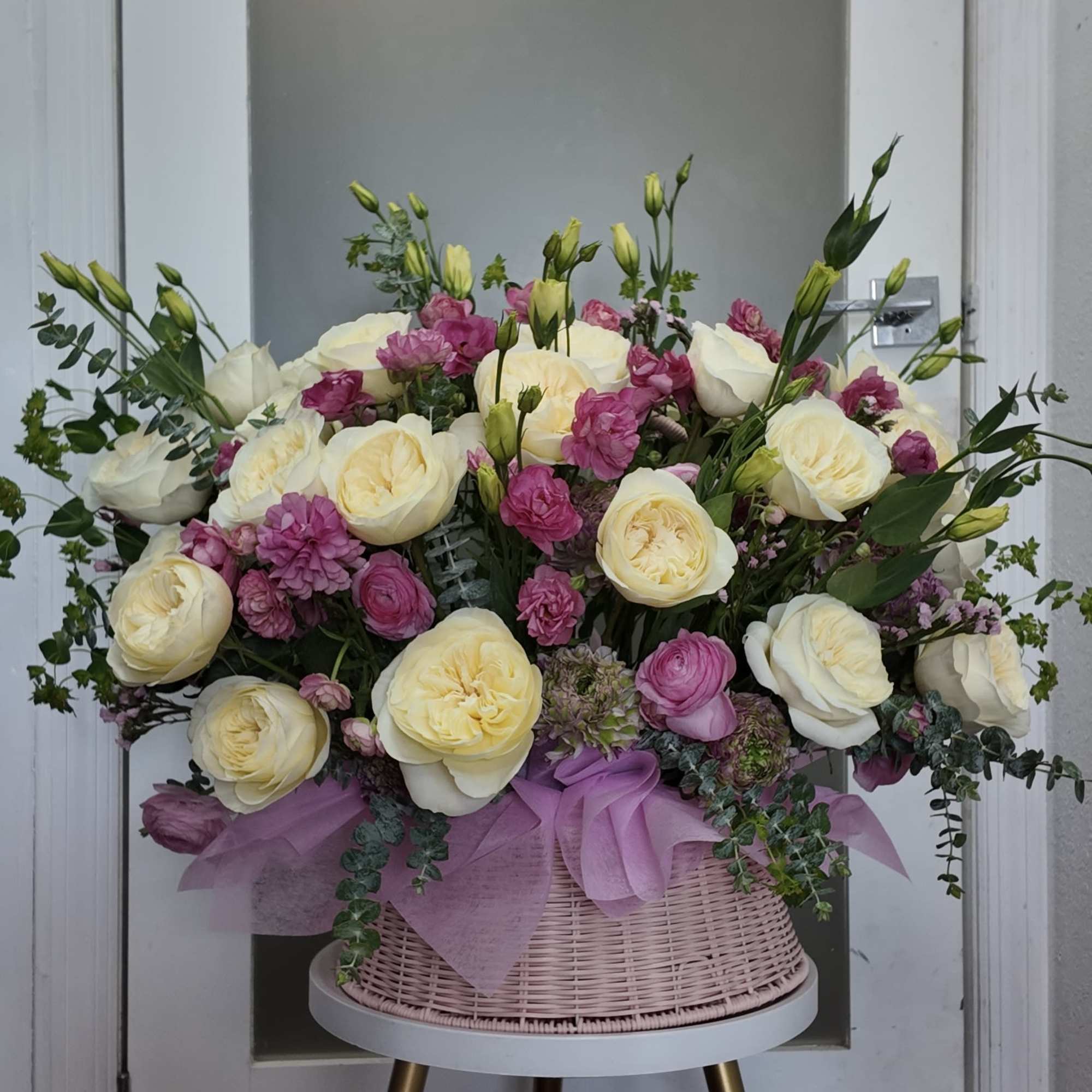 Large pink and cream rose arrangement in a woven basket
