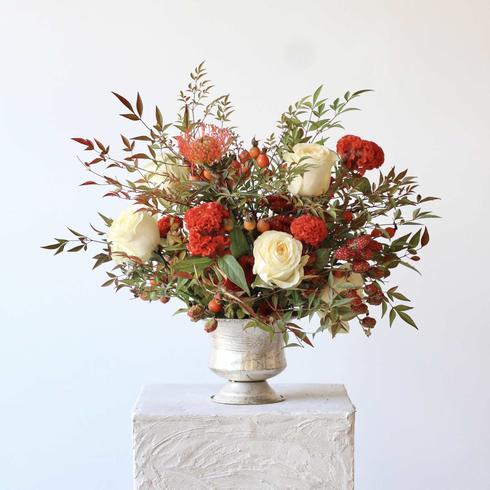 White and red floral arrangement in a silver vase
