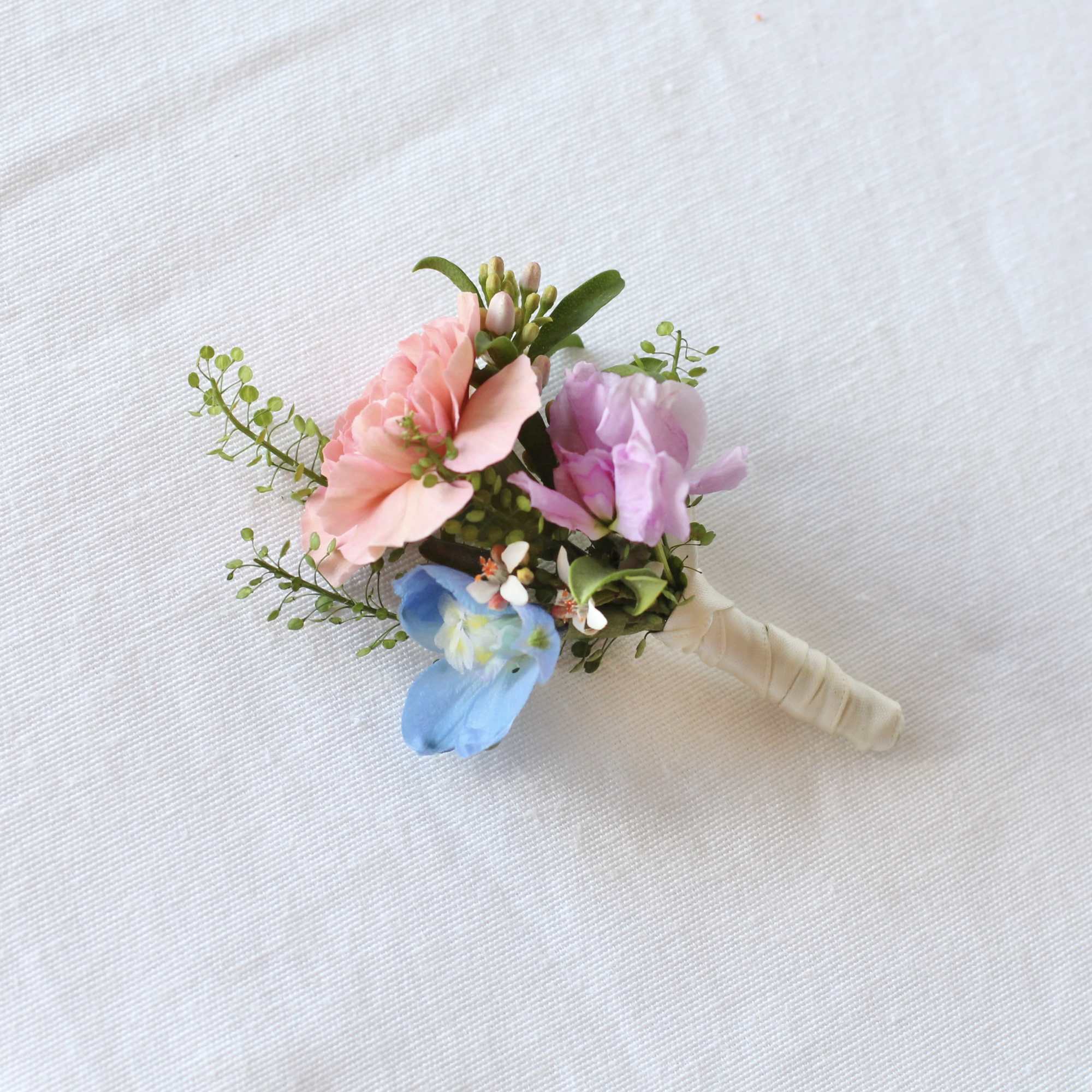 Small pastel boutonniere with pink, purple, and blue flowers