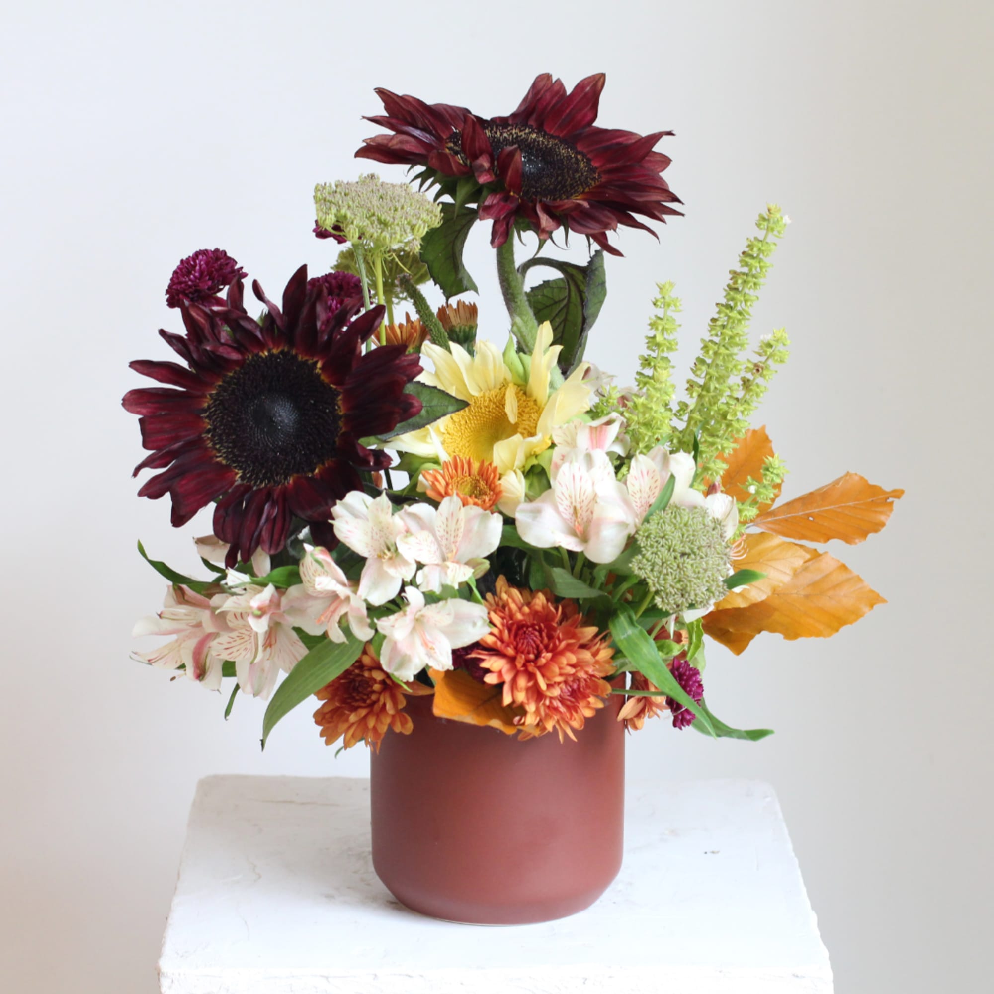 Mixed bouquet in a matte vase with burgundy sunflowers and white alstroemeria
