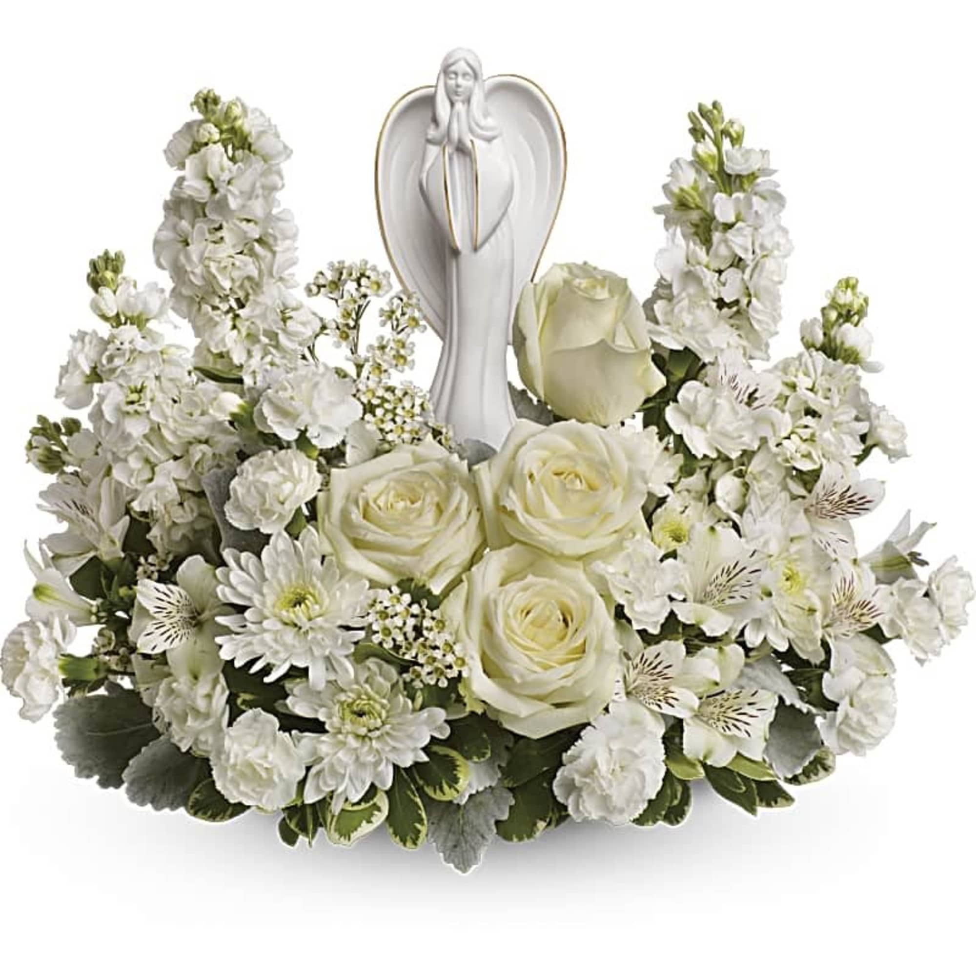 Low white floral arrangement with roses, mums, and other blooms surrounding a white ceramic angel figurine.