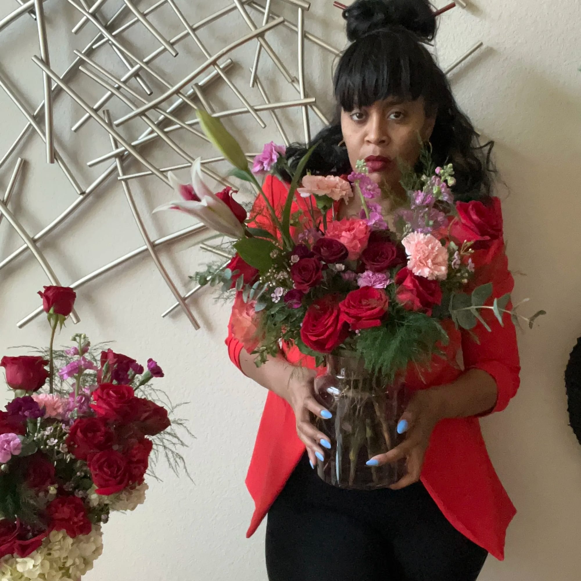 Woman holding a vase of red and pink flowers