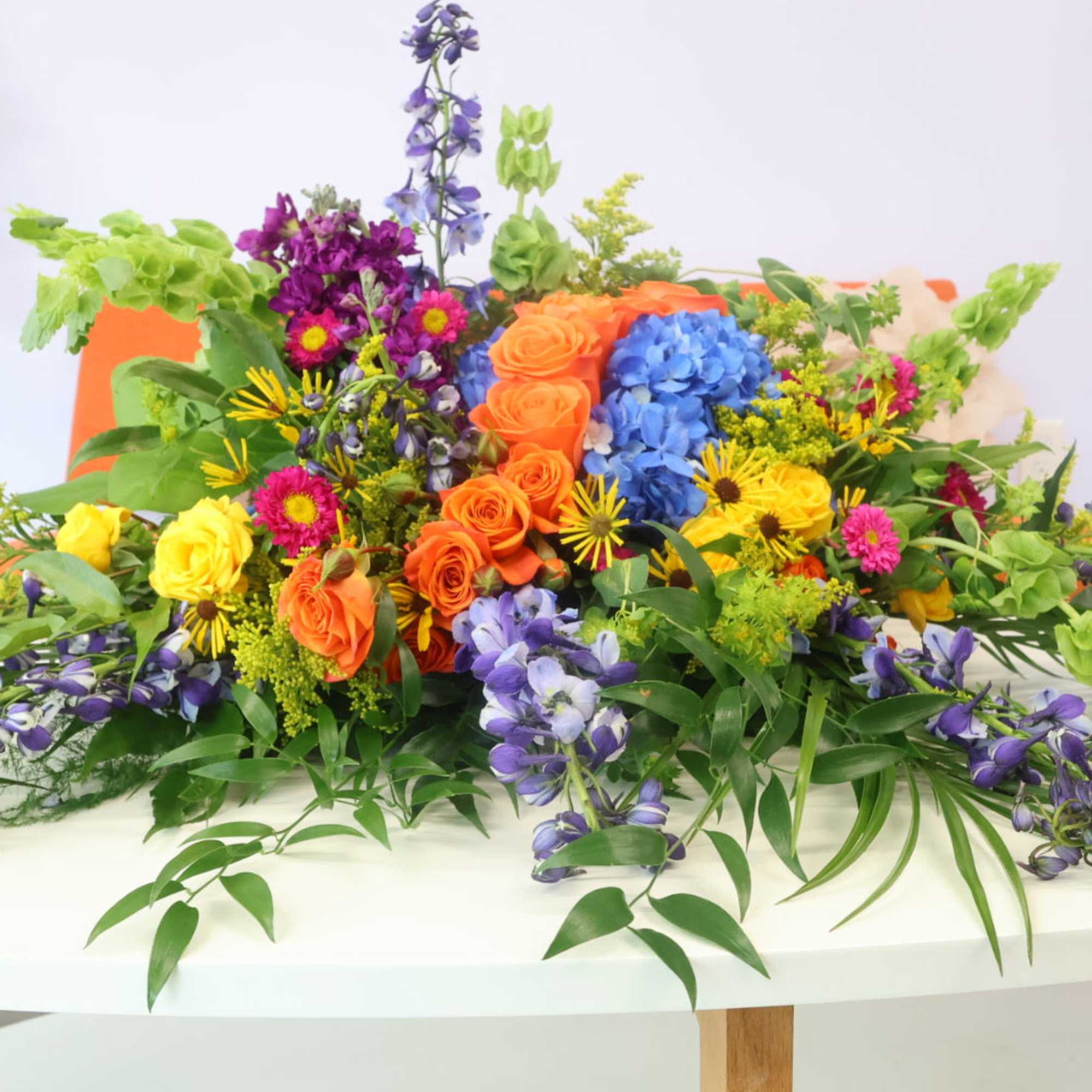Colorful mixed flower arrangement with roses, hydrangeas, and purple blooms on a table