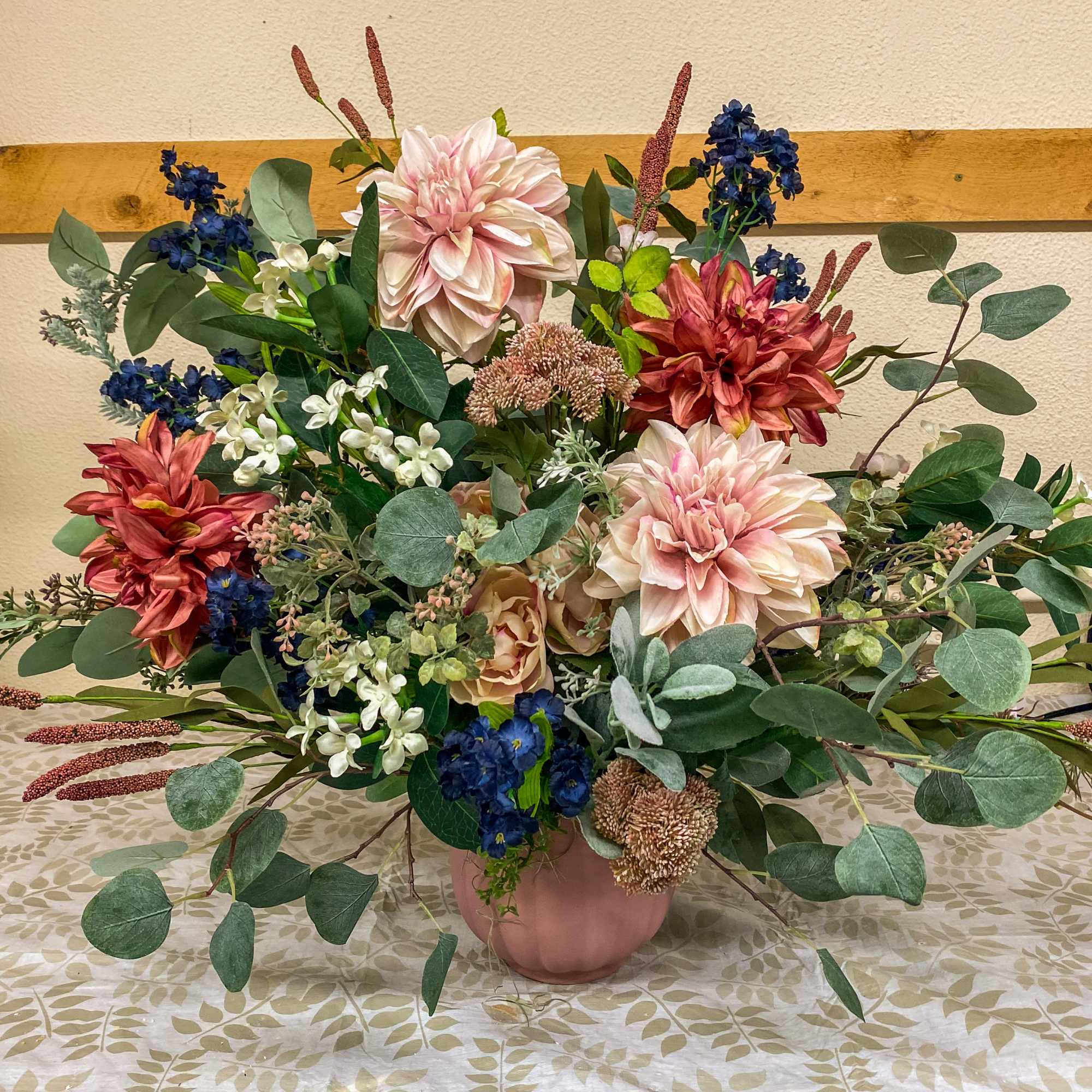 Large mixed floral arrangement in a pink vase with pink, blue, and white blooms